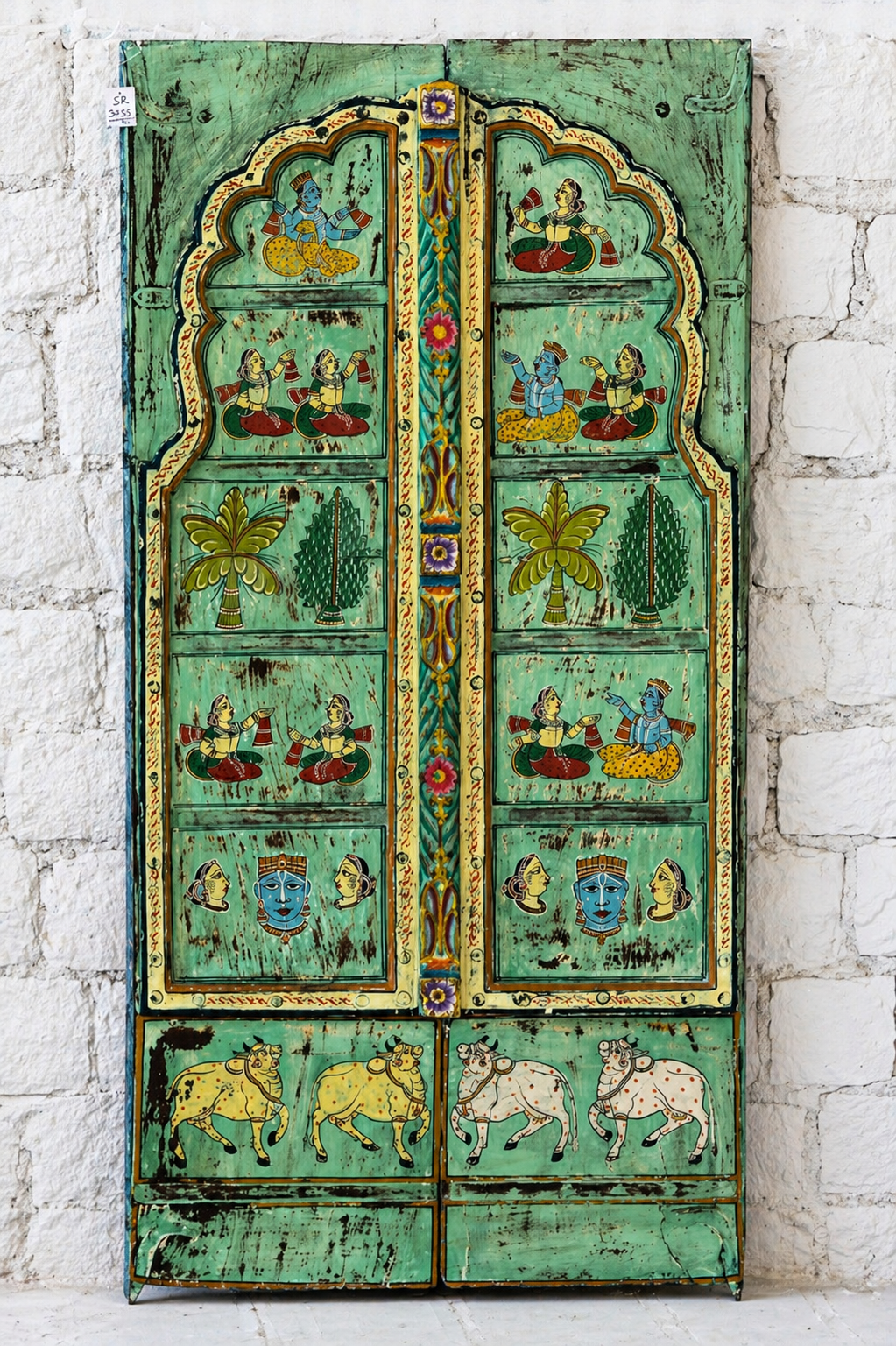 Decorative wooden panel with intricate carvings and paintings on a white brick wall background