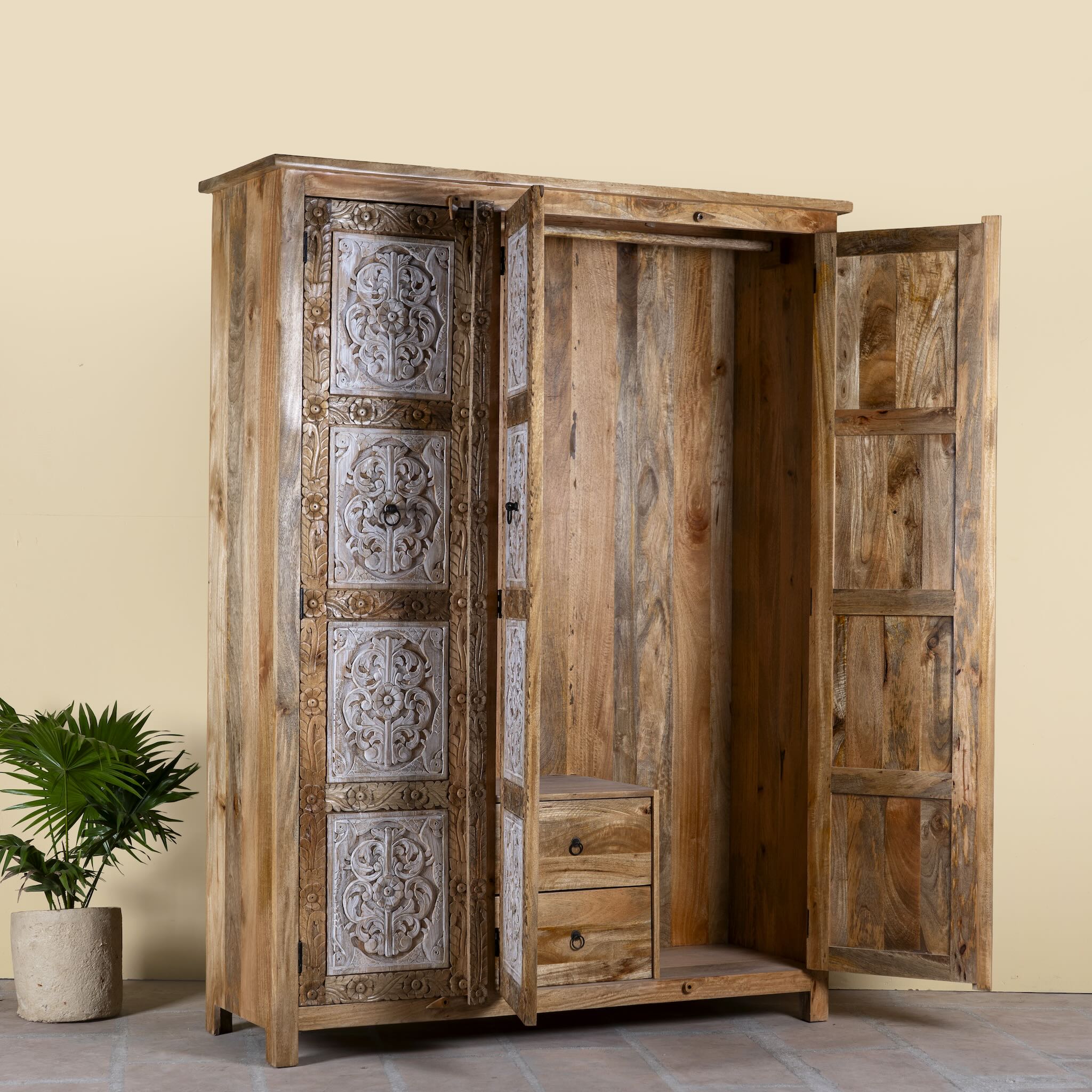 Side angle image with open doors of a hand carved wardrobe with floral design made of mango wood in vintage style.