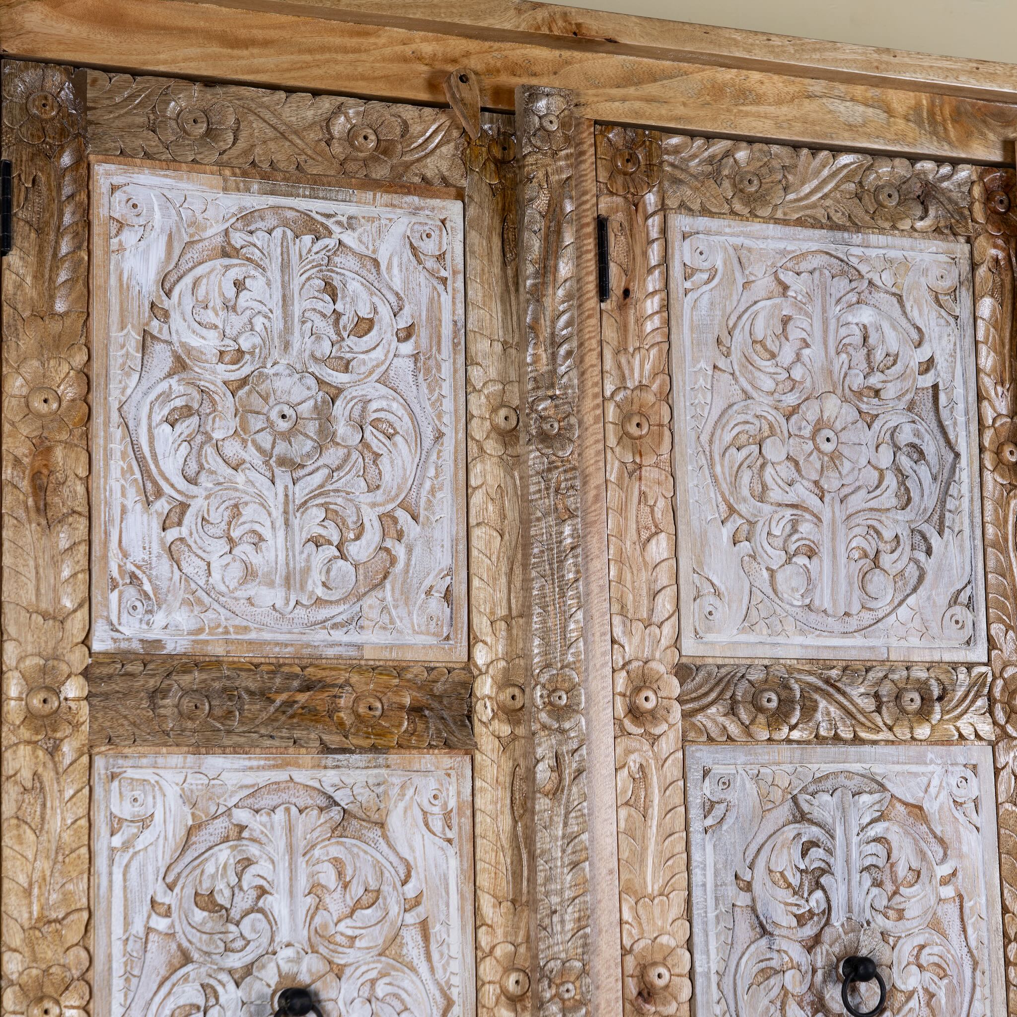 Close up image of a hand carved wardrobe with floral design made of mango wood in vintage style.