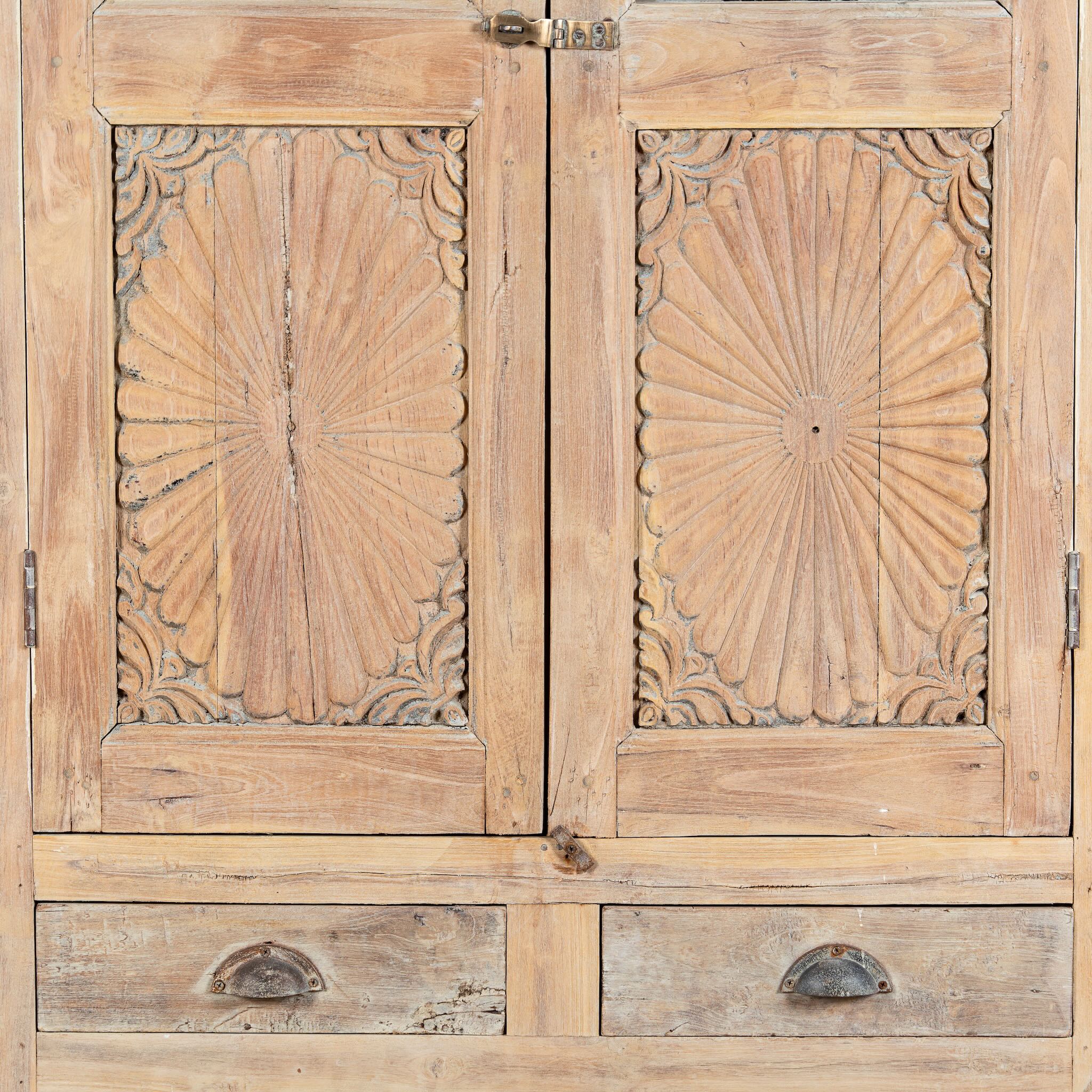 Close up image of a reclaimed teak wood showcase Aasta with Mediterranean design, featuring hand-carved doors, glass panels, and drawers. A unique piece of refurbished Indian furniture offering elegant display and practical storage.