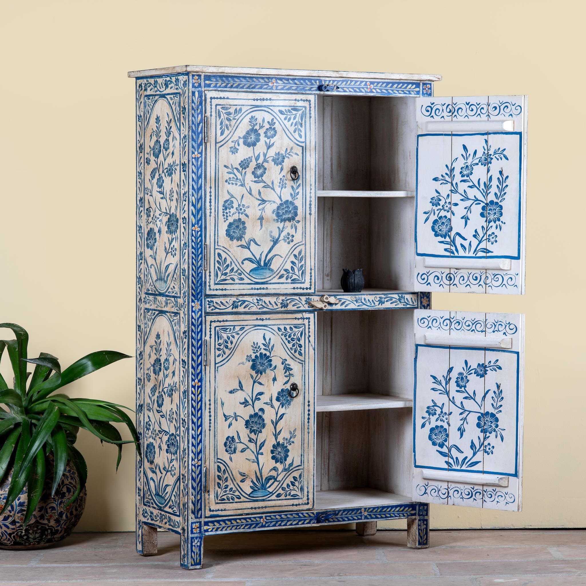 Side angle image with open doors of a unique hand painted wardrobe made of reclaimed wood with floral design, 4 doors and ample storage.