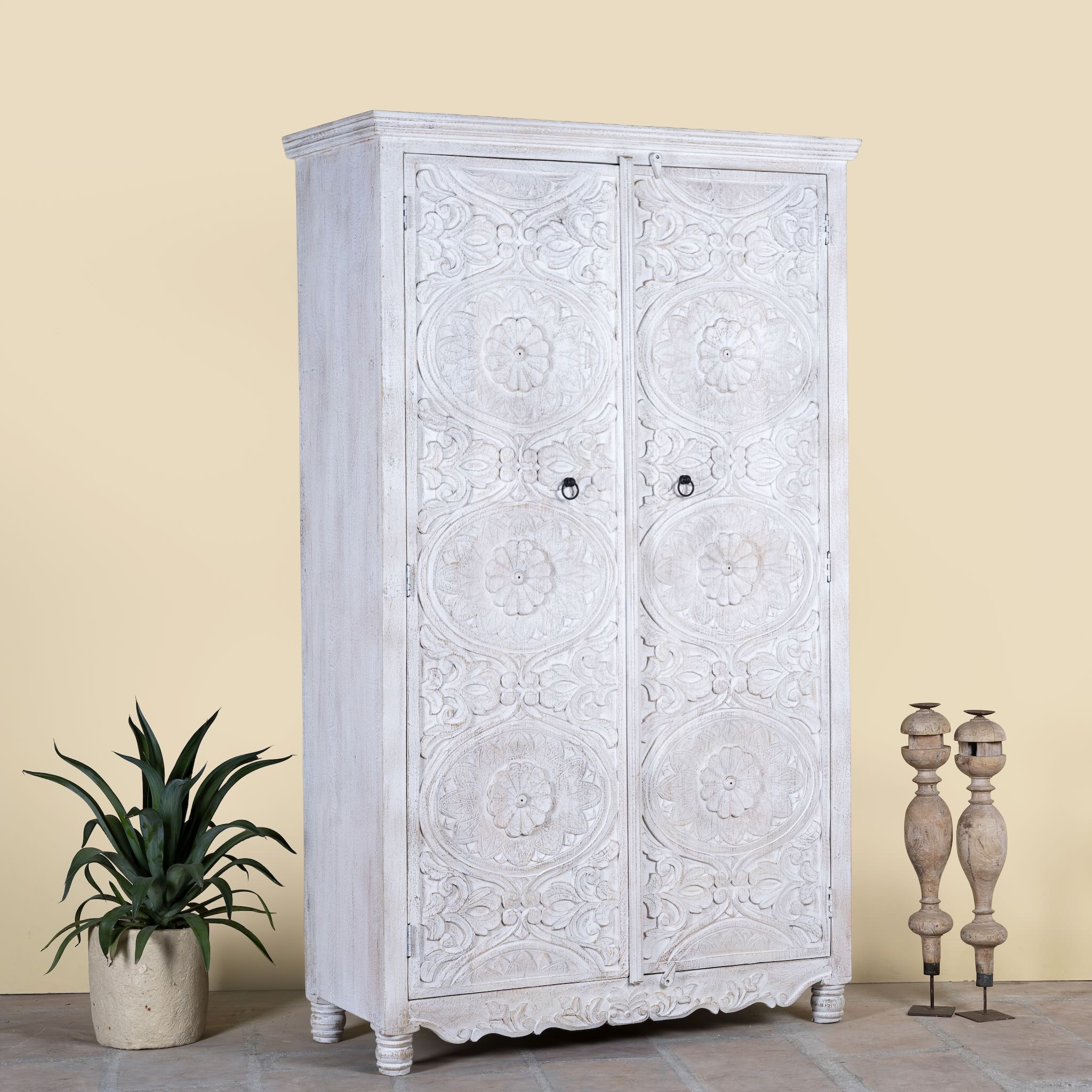 Side angle image of a hand carved white washed mango wood wardrobe in vintage design.