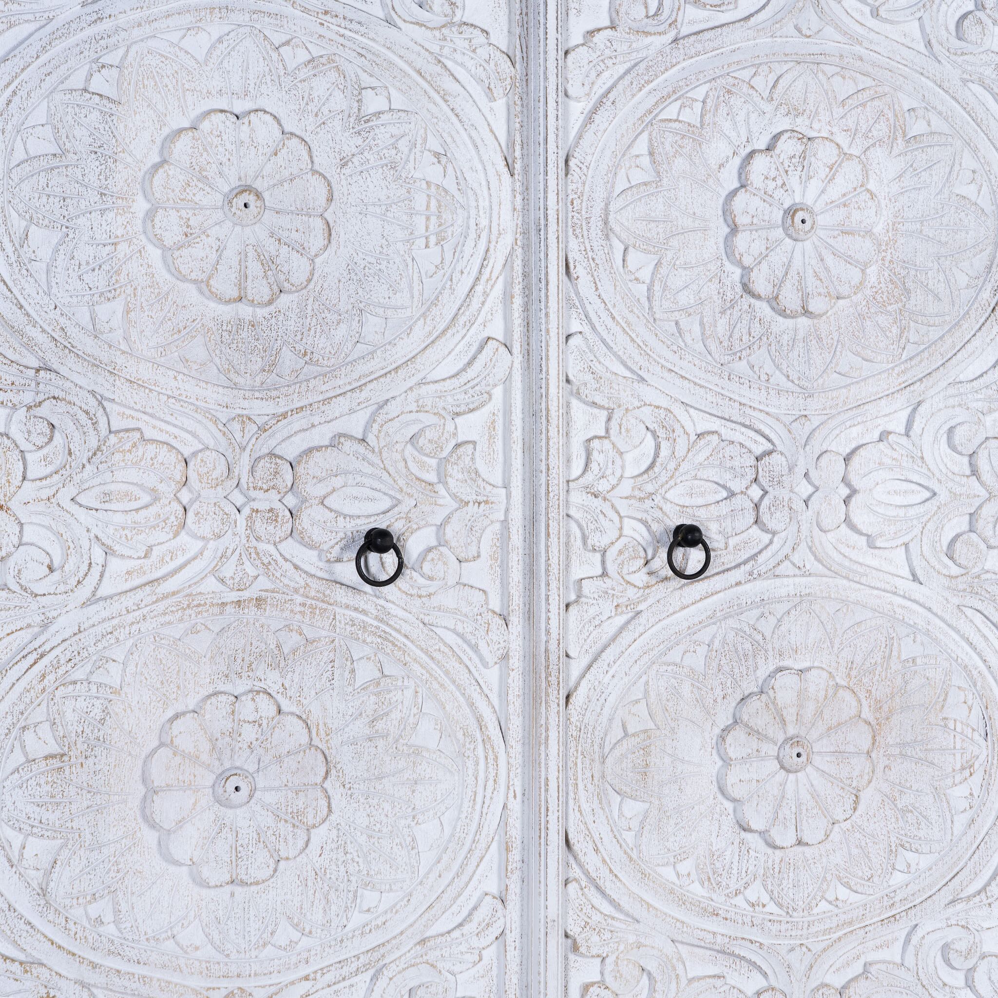 Close up image of a hand carved white washed mango wood wardrobe in vintage design.
