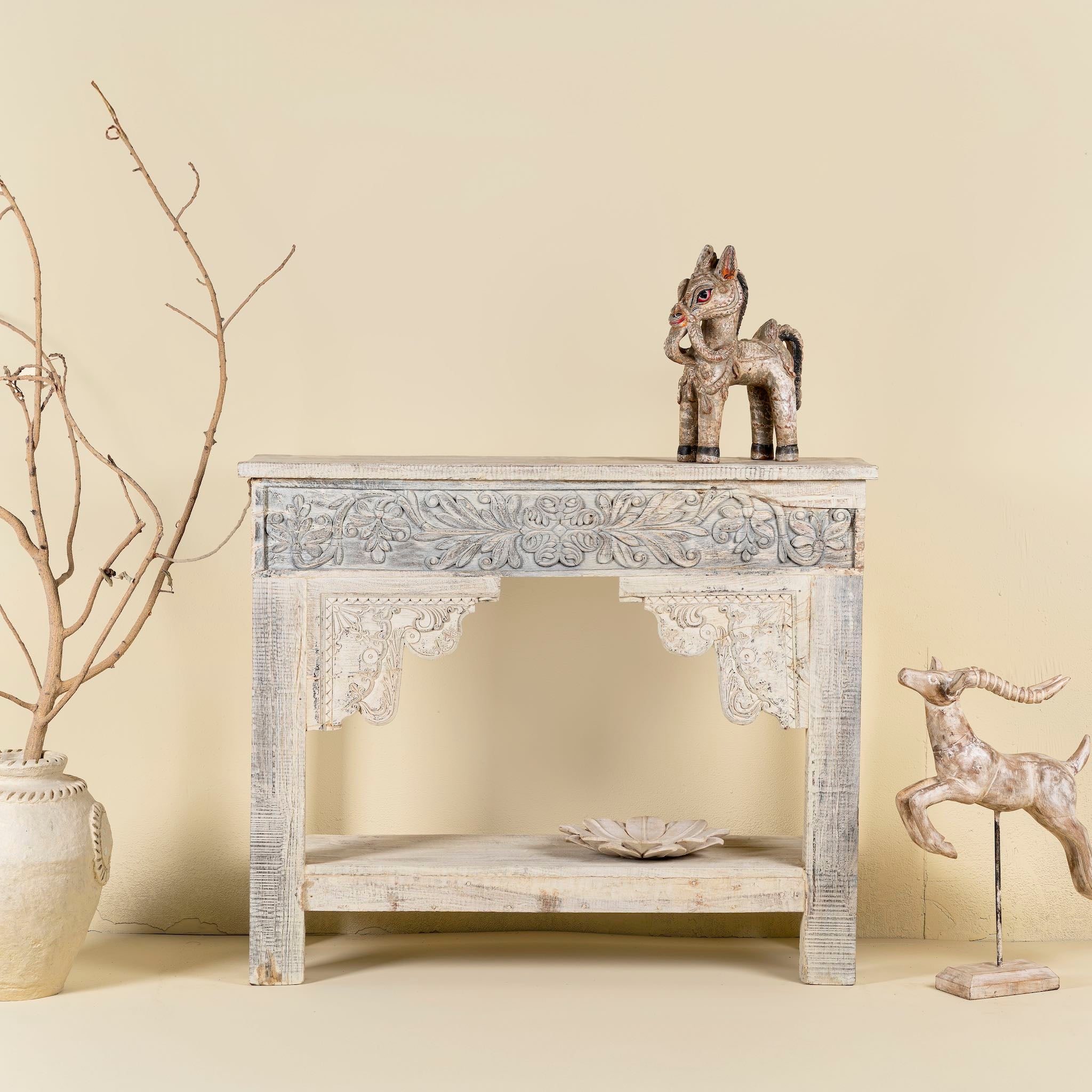 Front image of a handcrafted reclaimed teak wood console table with sandblasted finish, carved floral detailing, vintage corbels, and lower shelf; perfect for styling with vintage home accessories, 133 × 62 × 90 cm.