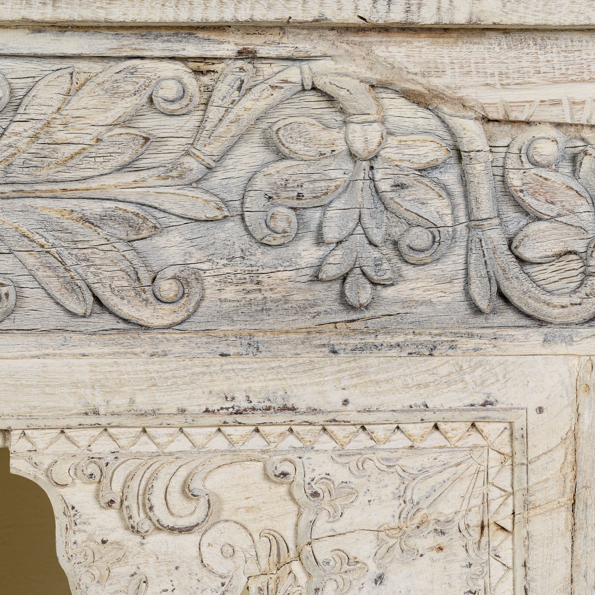 Close up image of a handcrafted reclaimed teak wood console table with sandblasted finish, carved floral detailing, vintage corbels, and lower shelf; perfect for styling with vintage home accessories, 133 × 62 × 90 cm.
