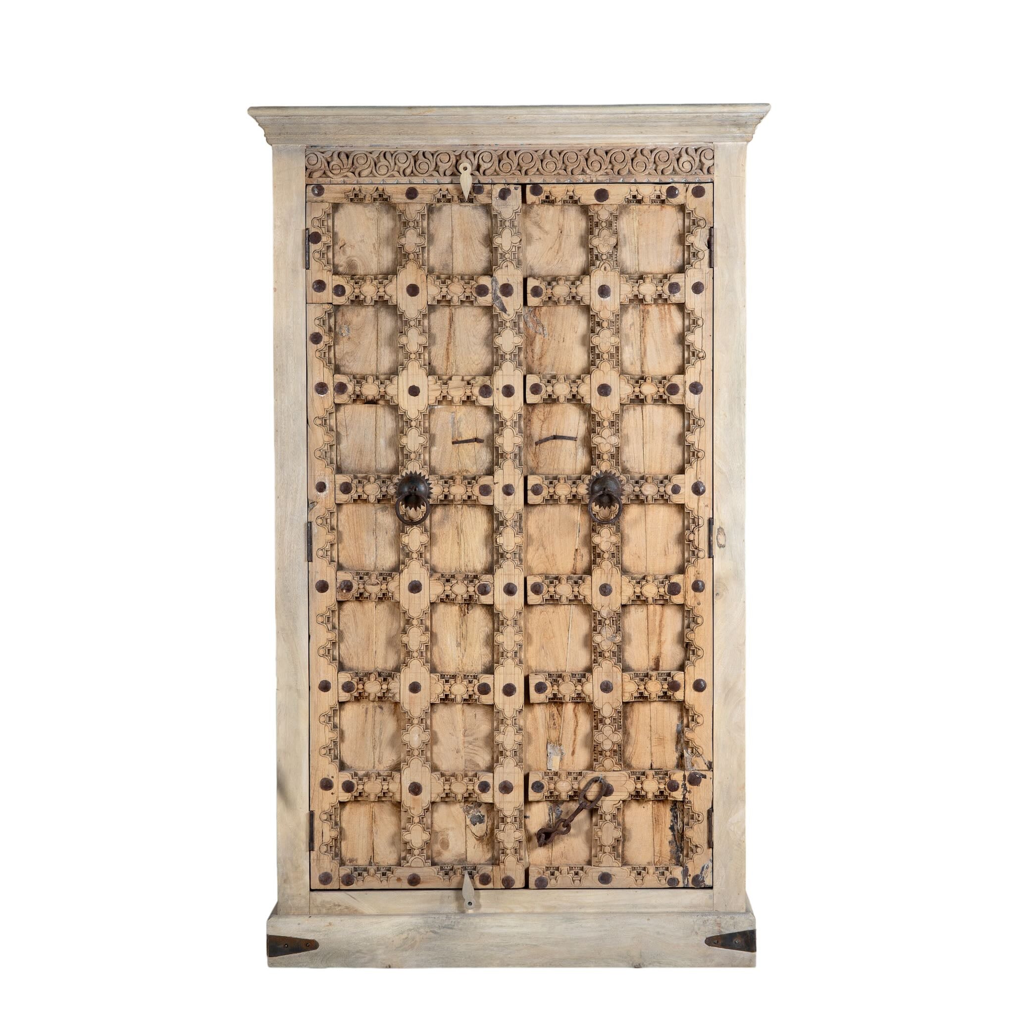White background image of a reclaimed wood wardrobe Akhila featuring an old Indian door front with carved details and iron hardware. A sustainable furniture piece and unique old door cabinet for soulful, heritage-inspired interiors.