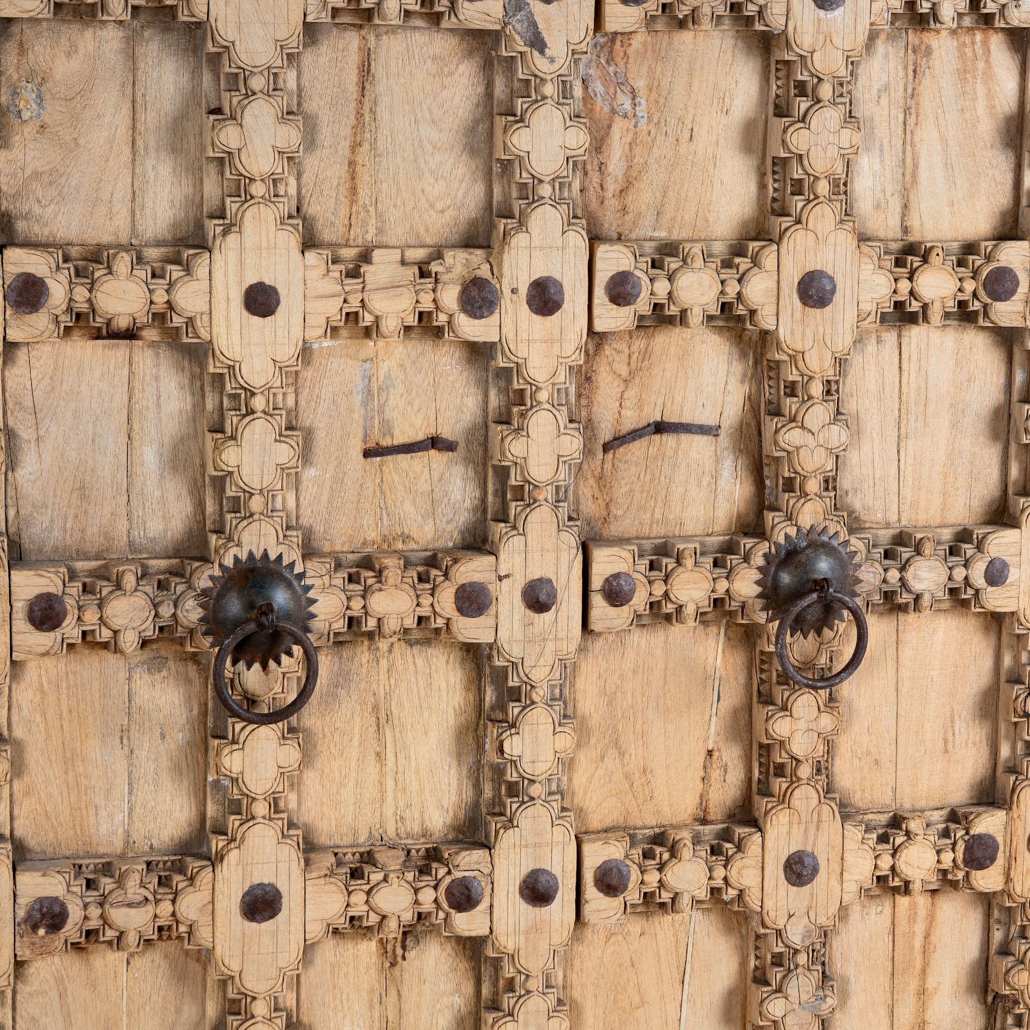 Close up image of a reclaimed wood wardrobe Akhila featuring an old Indian door front with carved details and iron hardware. A sustainable furniture piece and unique old door cabinet for soulful, heritage-inspired interiors.