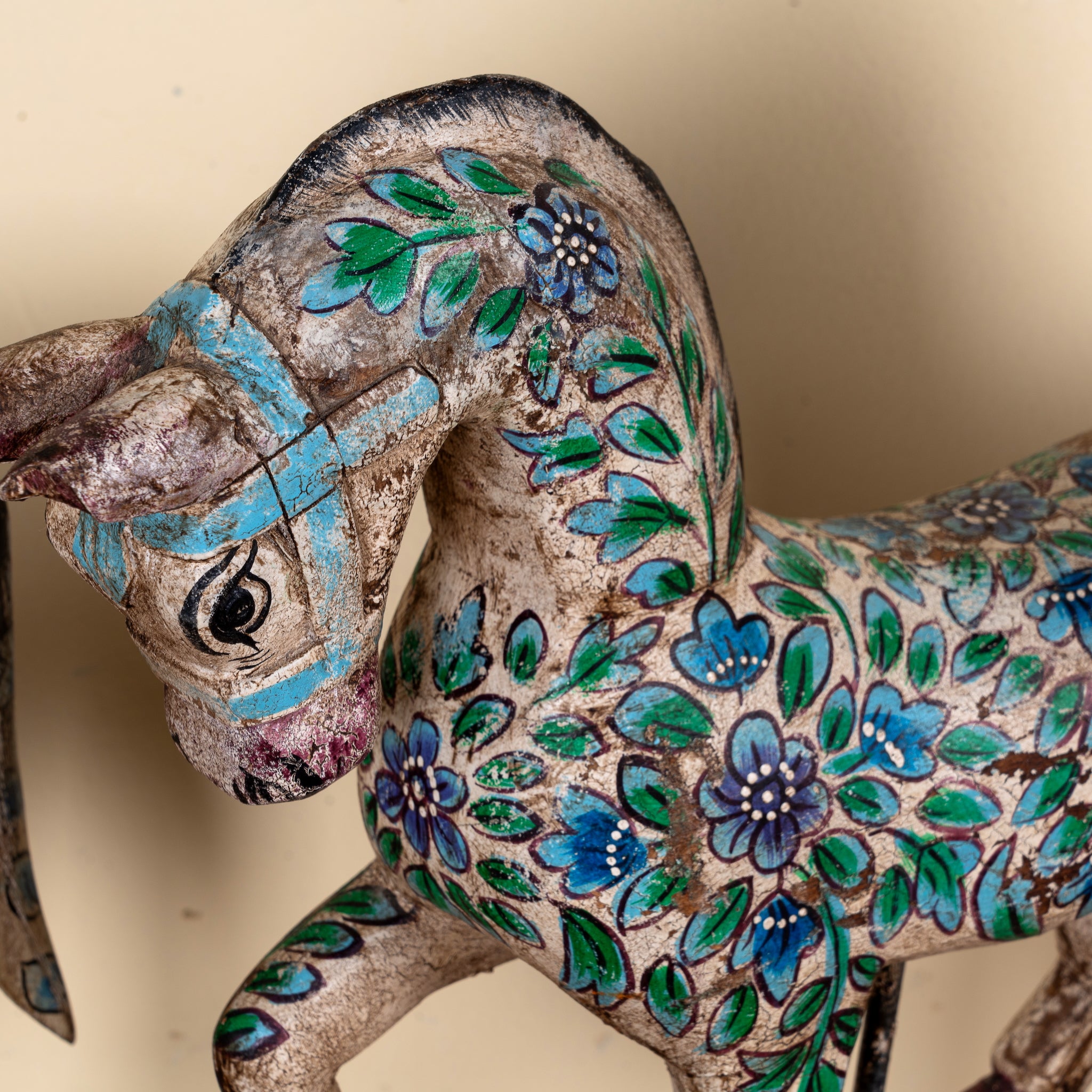Close up image of a Aksham hand painted wooden horse sculpture on an iron stand with colourful floral and ornamental detailing, 40x15x30cm.