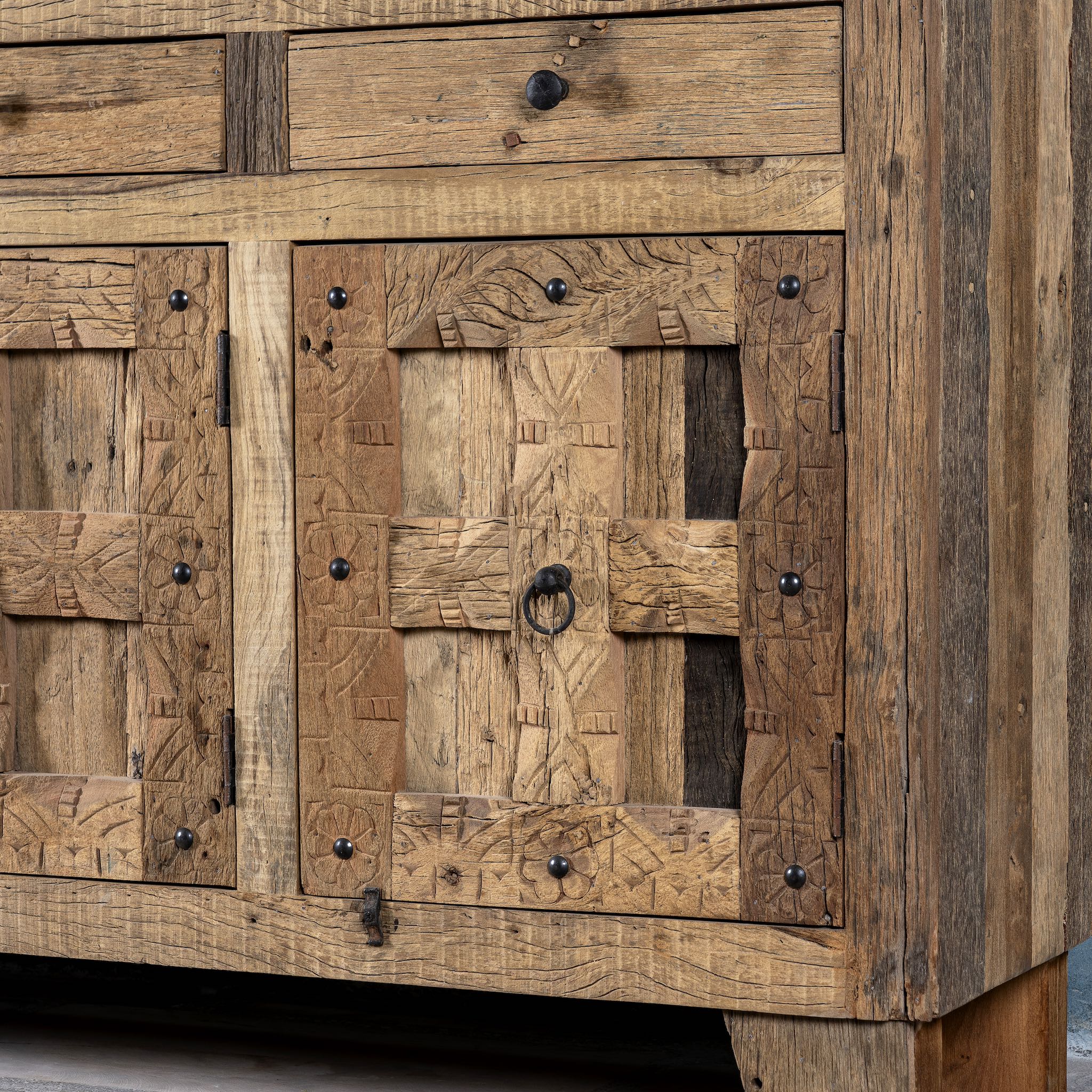Close up image of a rustic design sideboard made from reclaimed wood with panelled doors, drawers, and iron accents; 150 × 40 × 90 cm.