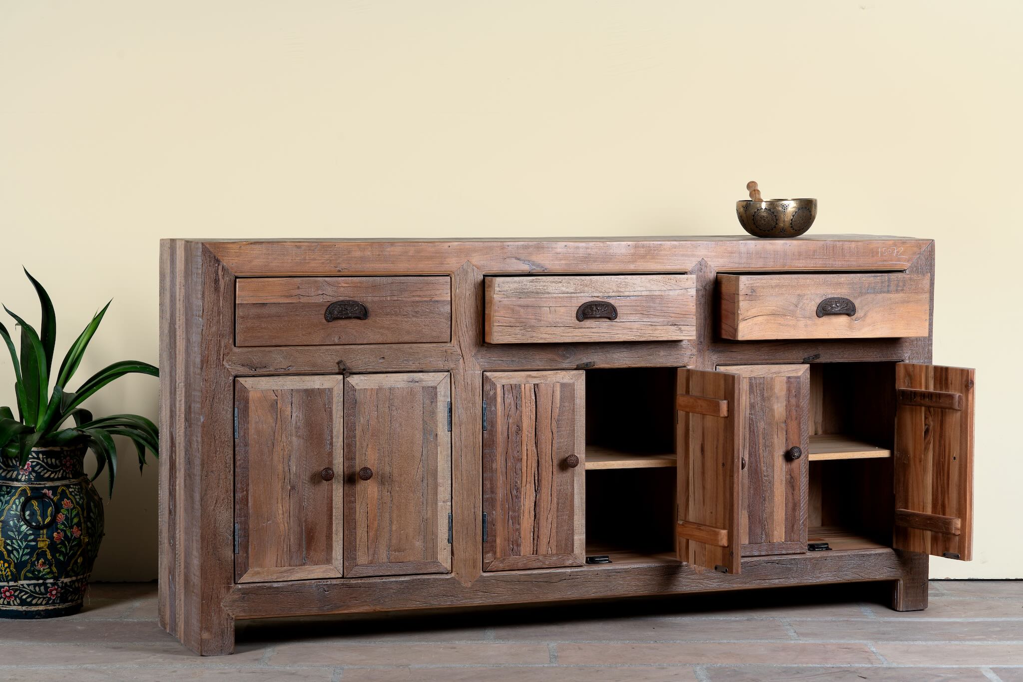 Side angle image with open doors of a reclaimed wood sideboard Amira in a rustic minimalist design, featuring three drawers and six doors with iron handles. A sustainable piece of living room furniture with natural textures and timeless appeal.