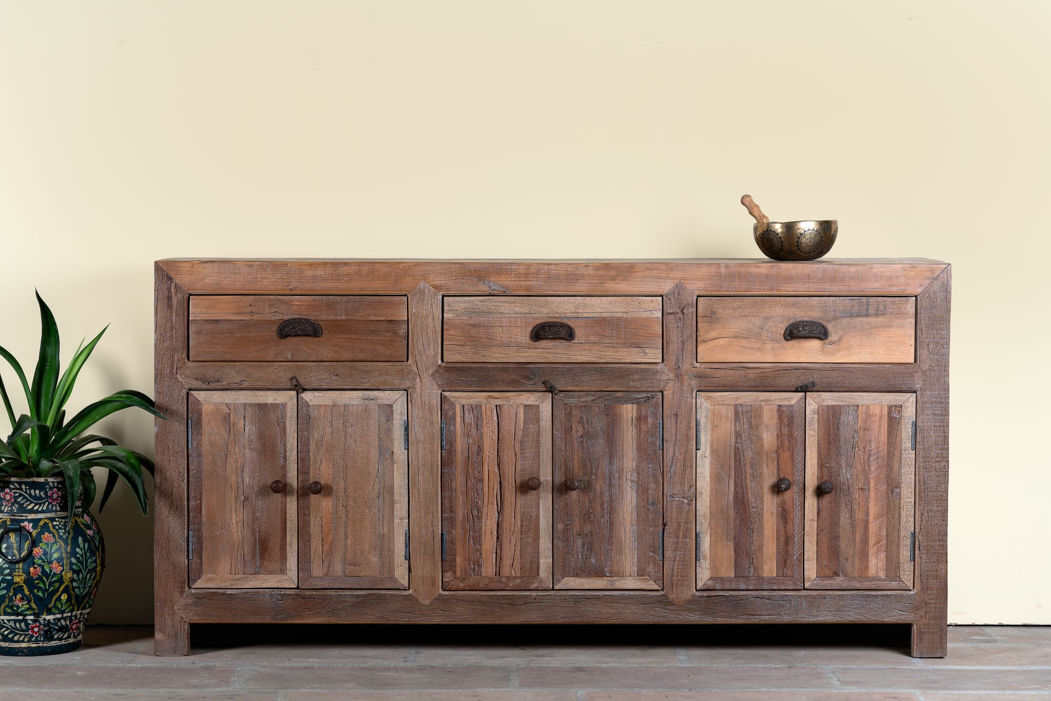 Reclaimed wood sideboard Amira in a rustic minimalist design, featuring three drawers and six doors with iron handles. A sustainable piece of living room furniture with natural textures and timeless appeal.