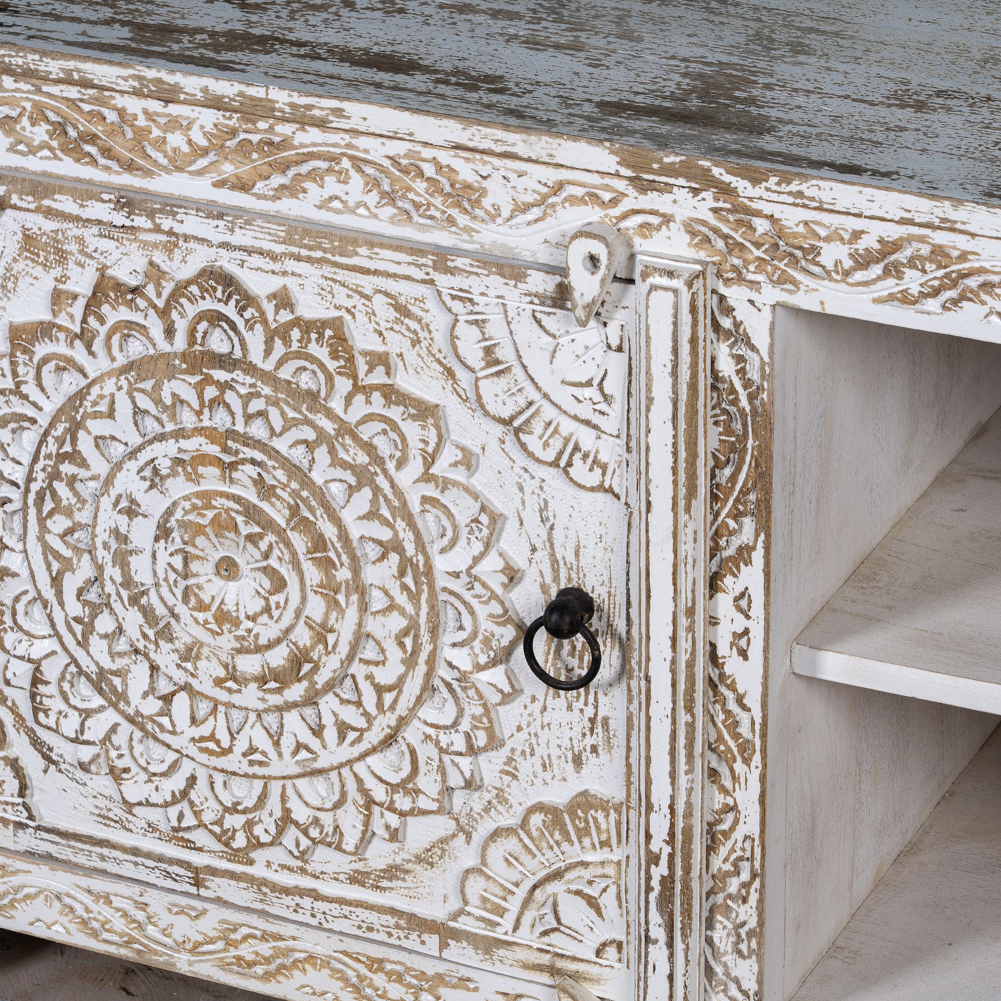 Close up picture of a white washed mango wood lowboard with carved floral doors and open shelving, 180 × 40 × 60 cm.