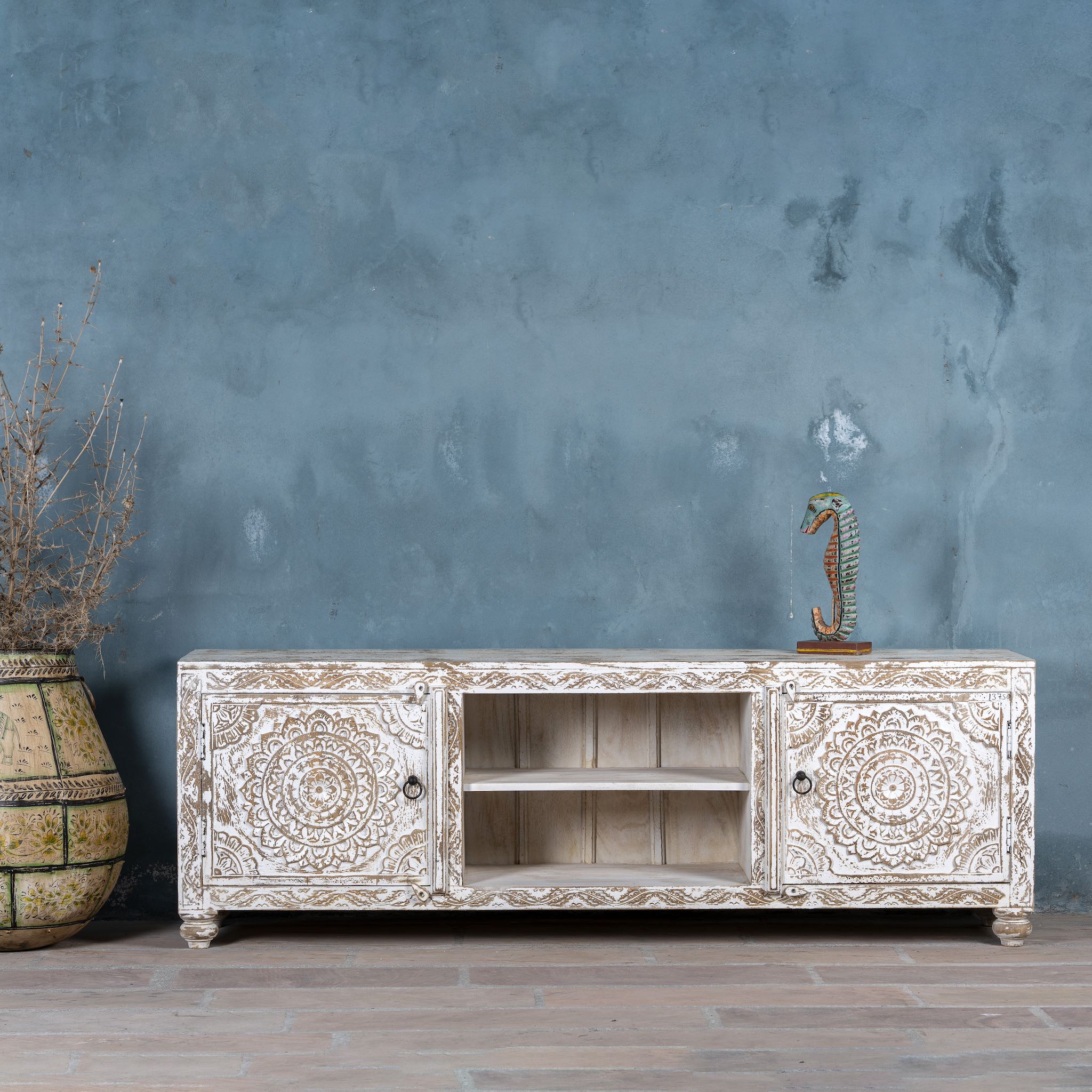 White washed mango wood lowboard with carved floral doors and open shelving, 180 × 40 × 60 cm.