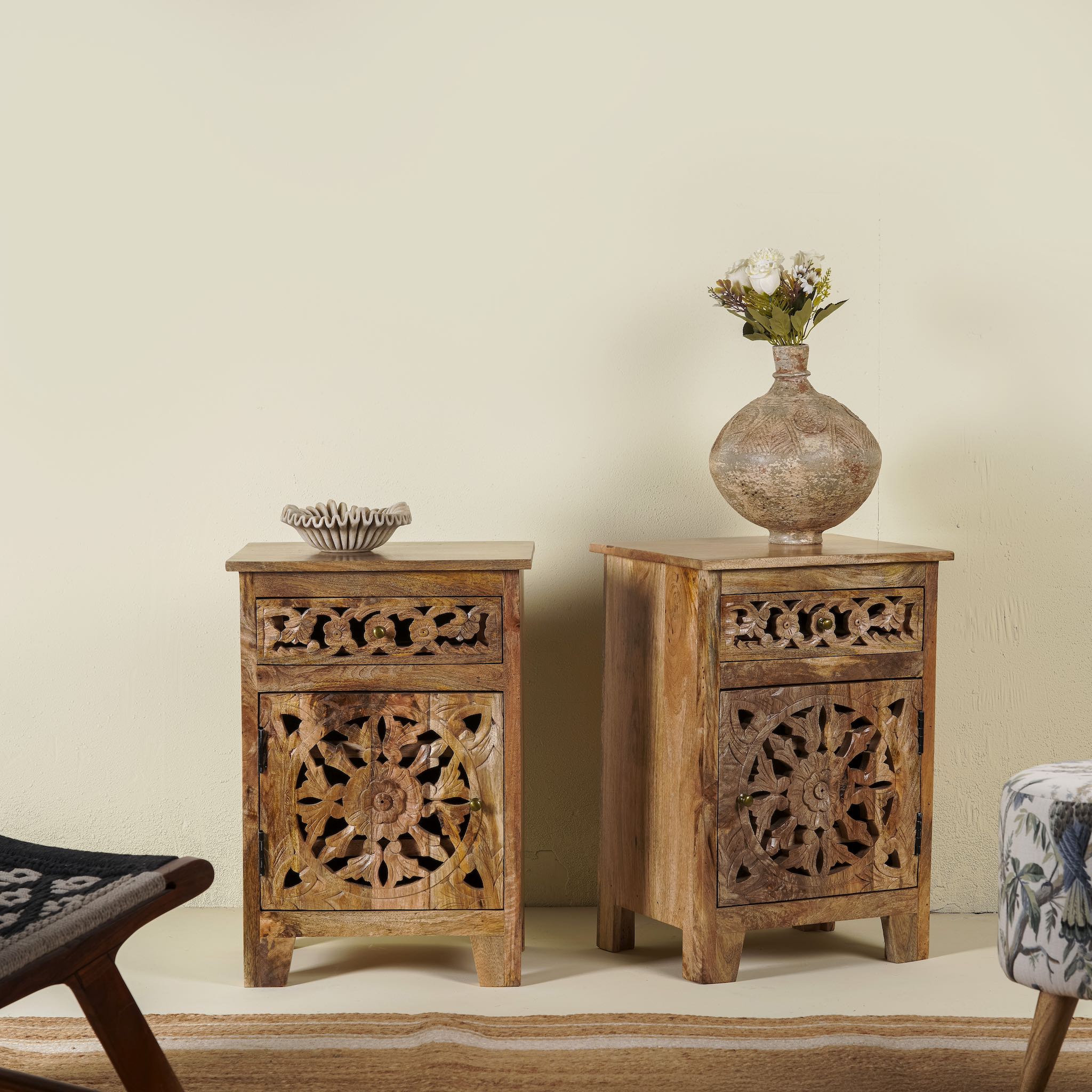 Side angle image of a pair of mango wood bedside tables with floral and geometric carvings; natural finish mango wood furniture ideal for bedroom furniture, 45 × 65 × 35 cm.