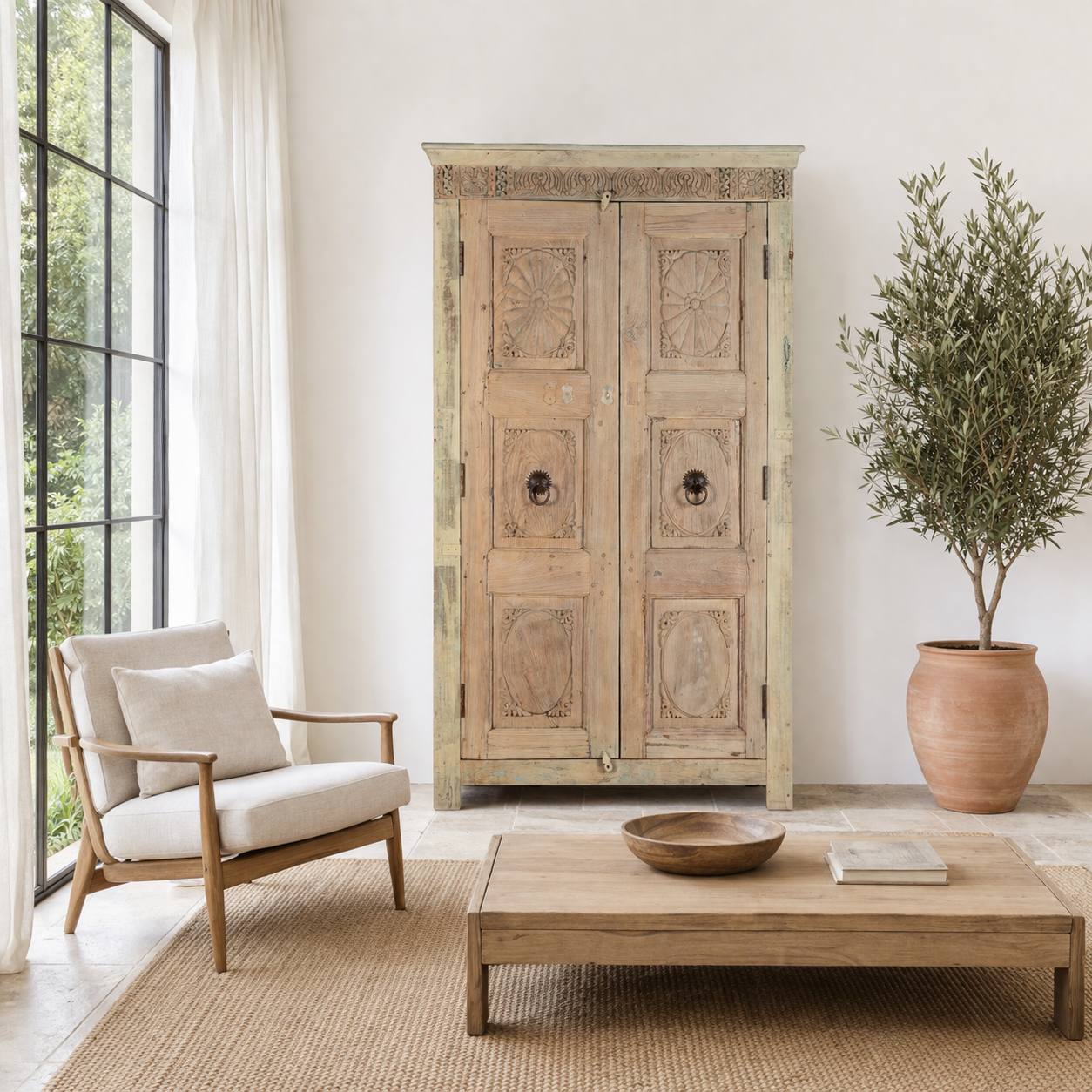 Lifestyle imagination of a reclaimed teak wood cabinet Anwika featuring a tall Mediterranean-style frame with hand-carved antique Indian doors. A unique piece of Indian furniture offering character-rich storage and timeless design.