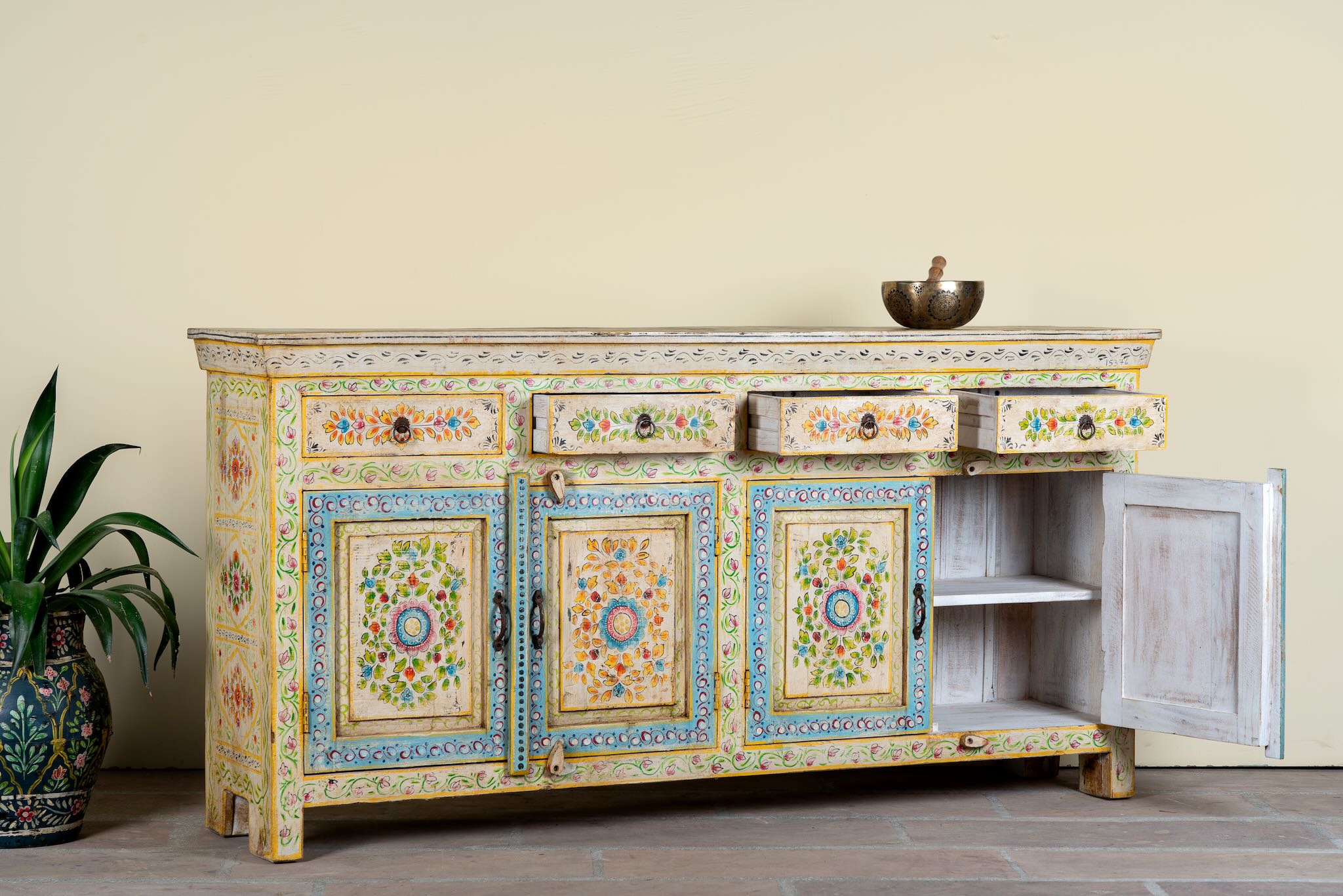 Side angle image with open drawers of a hand-painted reclaimed wood cabinet Anwita in Mediterranean Boho style with floral motifs, four drawers, and four doors. A colourful and sustainable statement piece for boho chic living room décor.