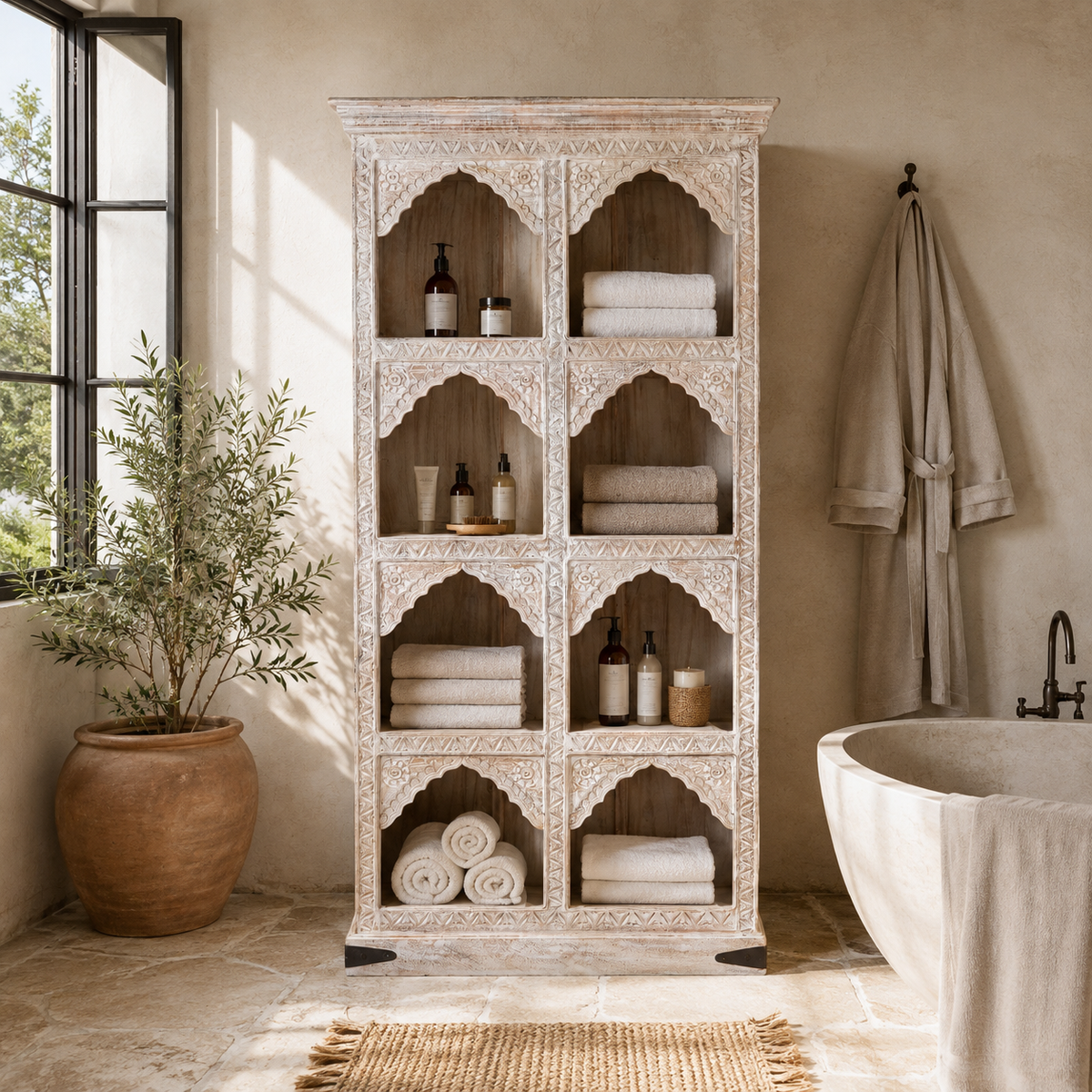 Lifestyle image of a hand-carved mango wood shelving unit with Moroccan arches and whitewashed finish; perfect as an entryway shelf or display piece, 180 × 90 × 40 cm.