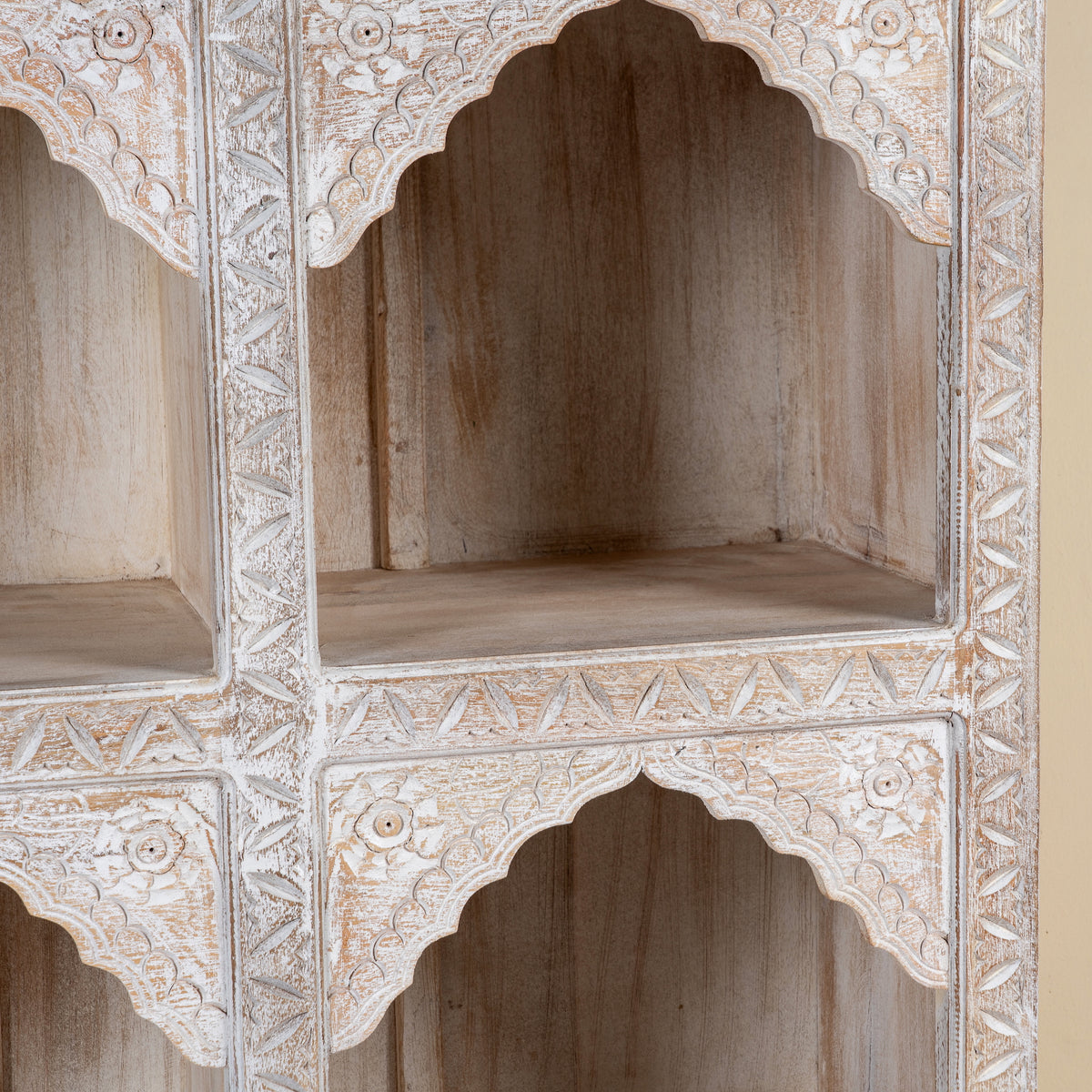Close up image of a hand-carved mango wood shelving unit with Moroccan arches and whitewashed finish; perfect as an entryway shelf or display piece, 180 × 90 × 40 cm.
