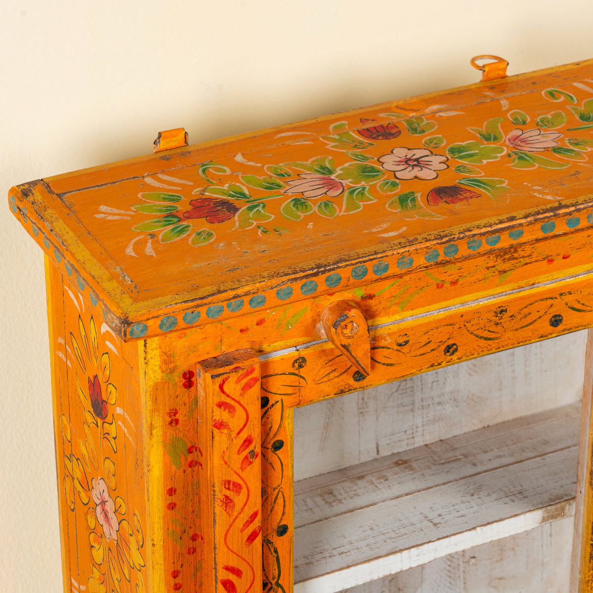 Close up image of a Arnavraj orange hand painted reclaimed wood vintage cabinet with floral motifs glass door and white interior 60cm