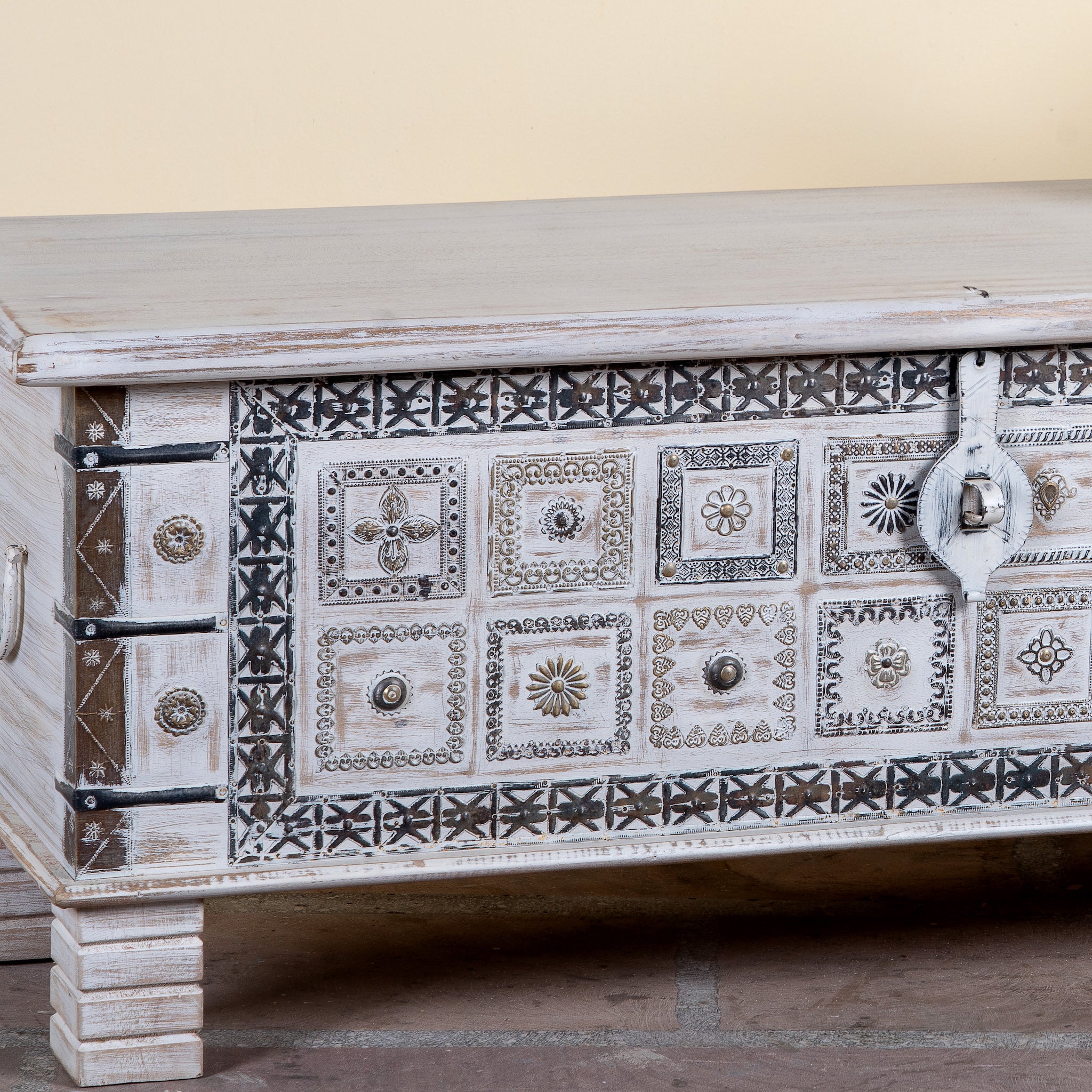 Close up image of a Aryav whitewashed mango wood coffee table chest with decorative iron fittings 116cm
