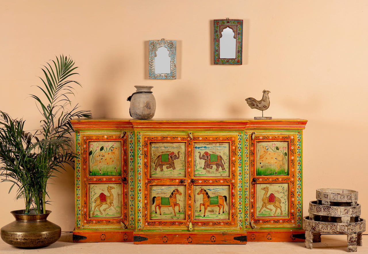 A hand-painted sideboard made of reclaimed wood with vibrant, colorful artistic motifs on the doors and vintage style accents.