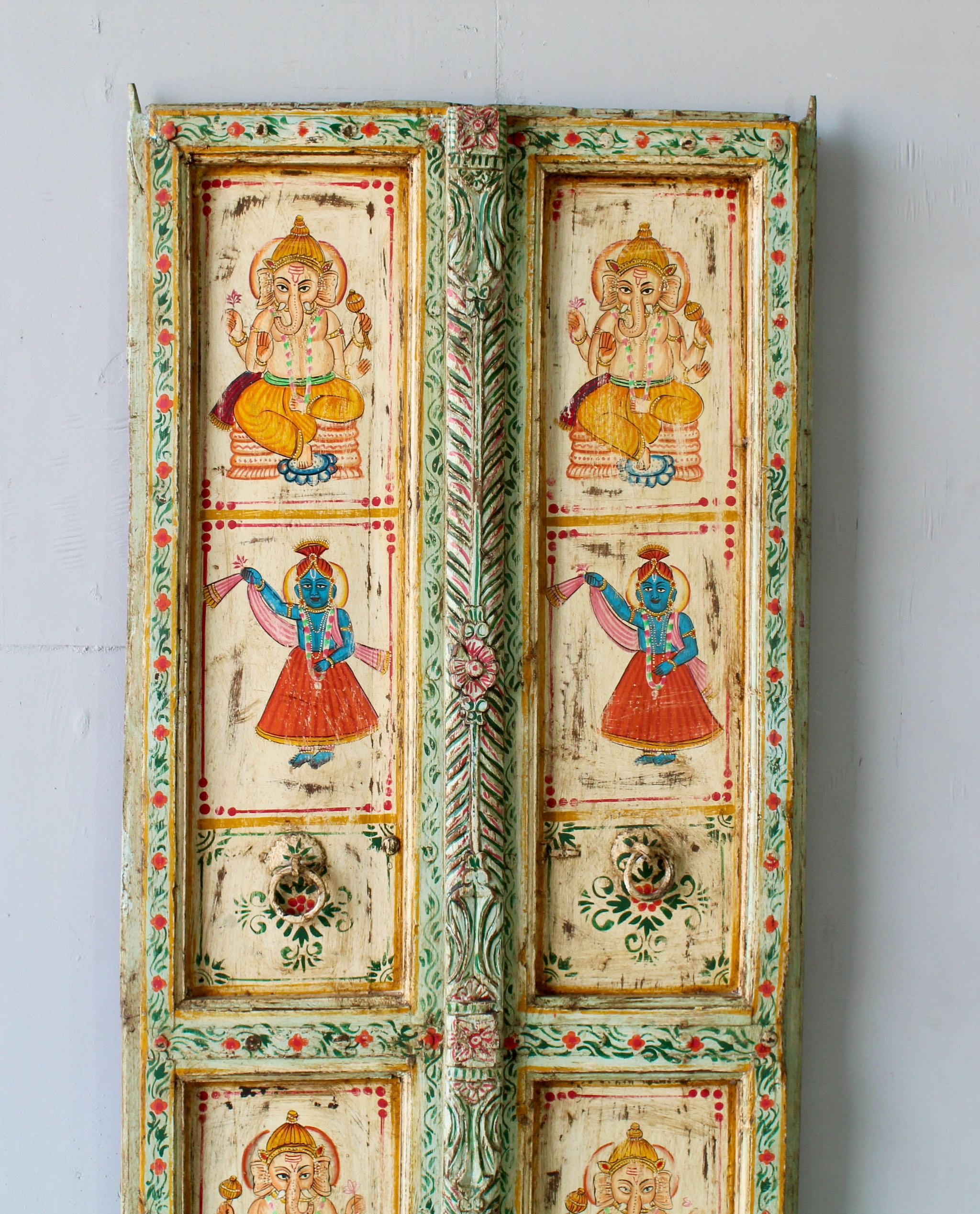 Close up image of a Aum hand-painted teak door panel featuring Goddess Lakshmi and traditional dancers, framed by leafy green carvings—a spiritual and unique Indian wall decoration repurposed from antique teak architecture.