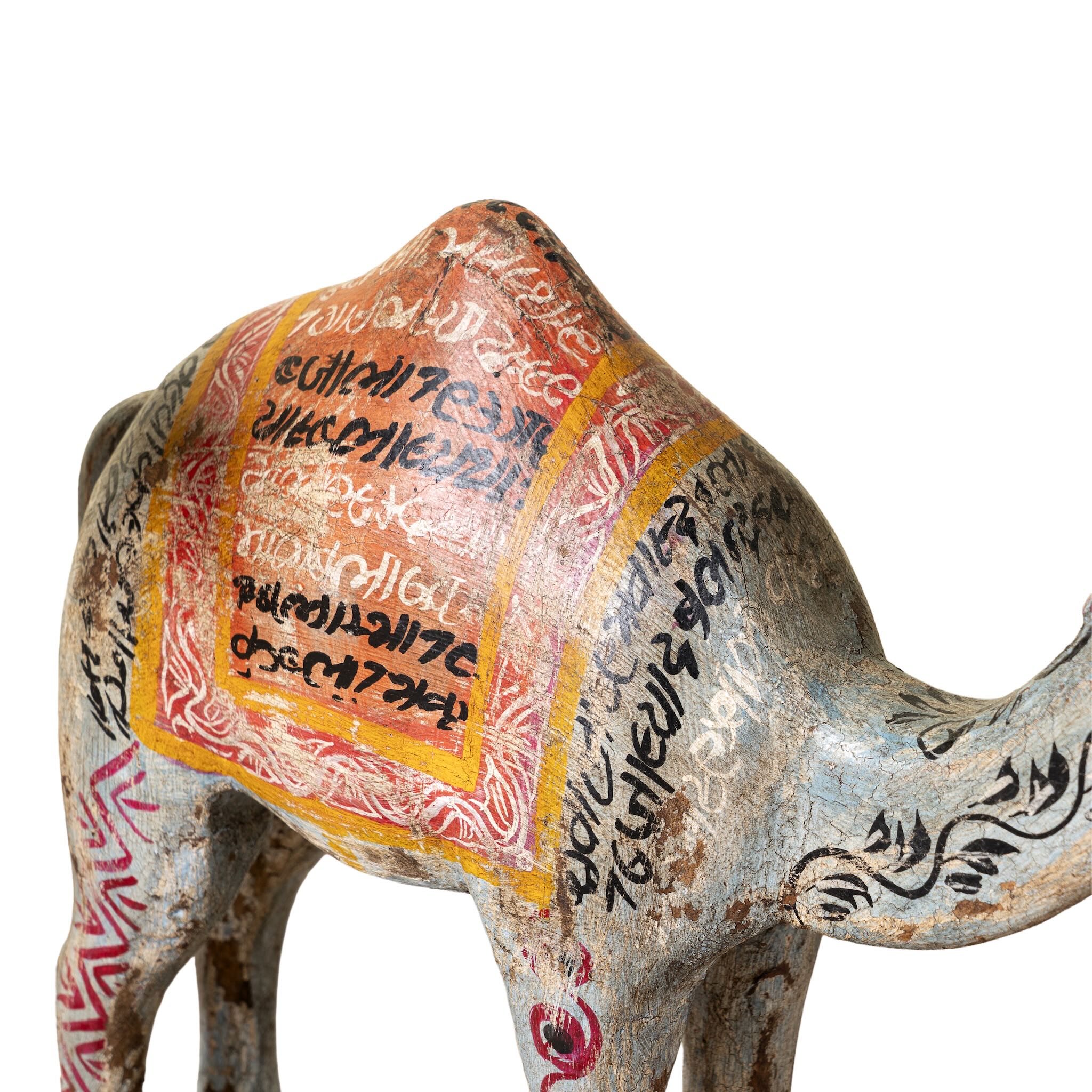 Close up image of a hand-painted wooden dromedary sculptures in different colours – decorative camel figures made from reclaimed wood, inspired by Indian folk art.