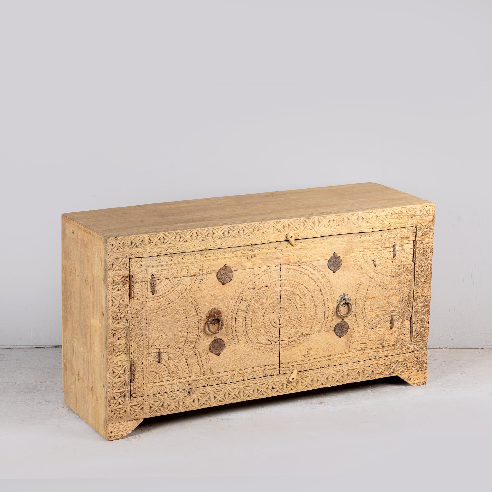 Side angle image of a Ayra reclaimed teak wood sideboard with hand carved Orissa house door elements and original iron fittings 123cm