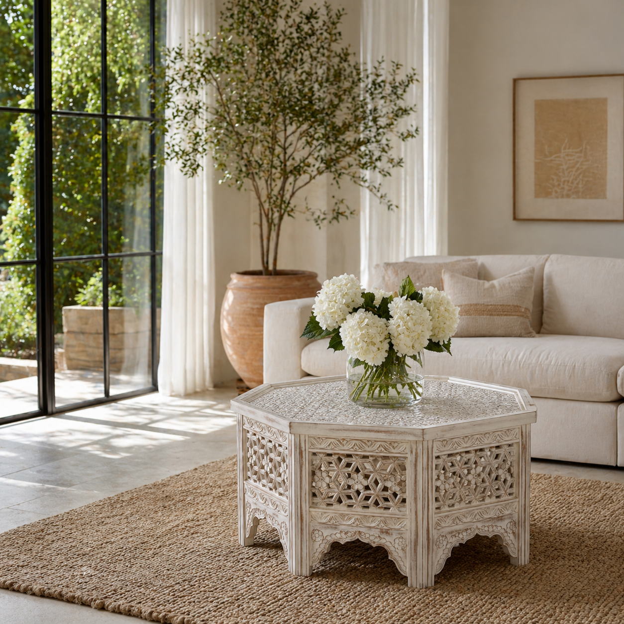 Lifestyle image of a octagonal mango wood coffee table with floral carvings and white wash finish; hand-carved and rustic, 90 × 90 × 46 cm.