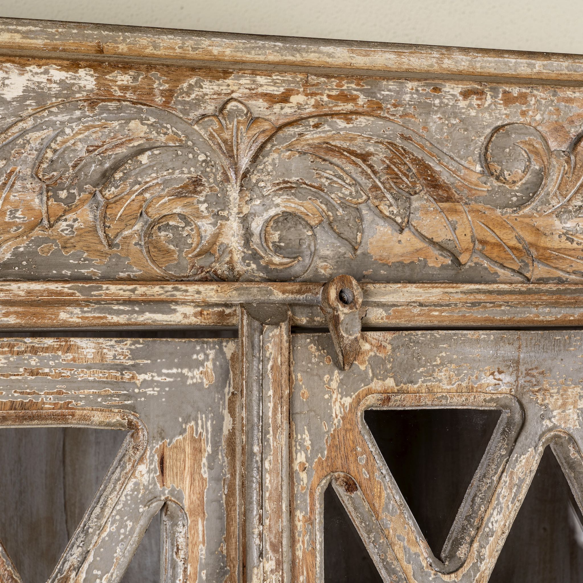 Close up image of a vintage display cabinet made from solid mango wood with glass doors and shelving – handcrafted Ibiza-style showcase with carved details.