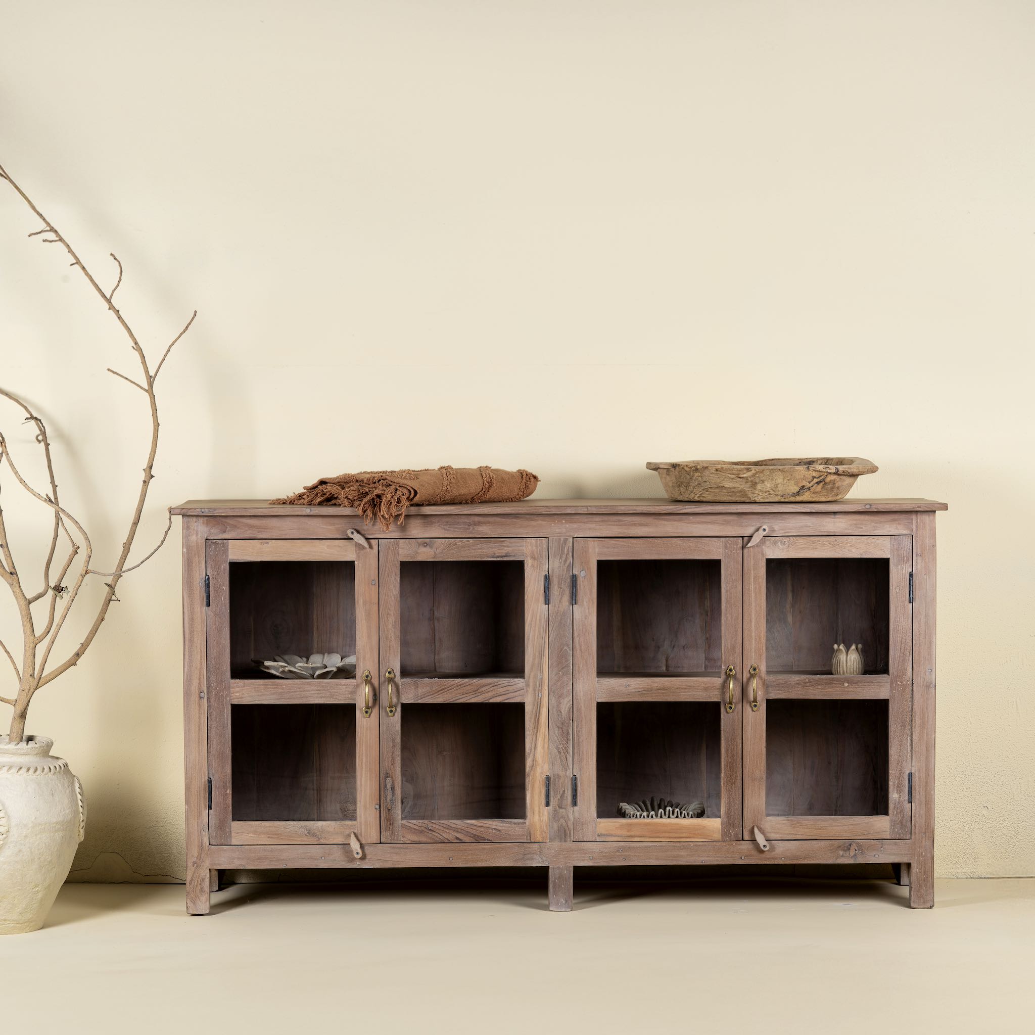 Reclaimed wood dresser with four glass doors, teak wood showcase cabinet with brass handles and wooden latches, 170 × 40 × 90 cm.