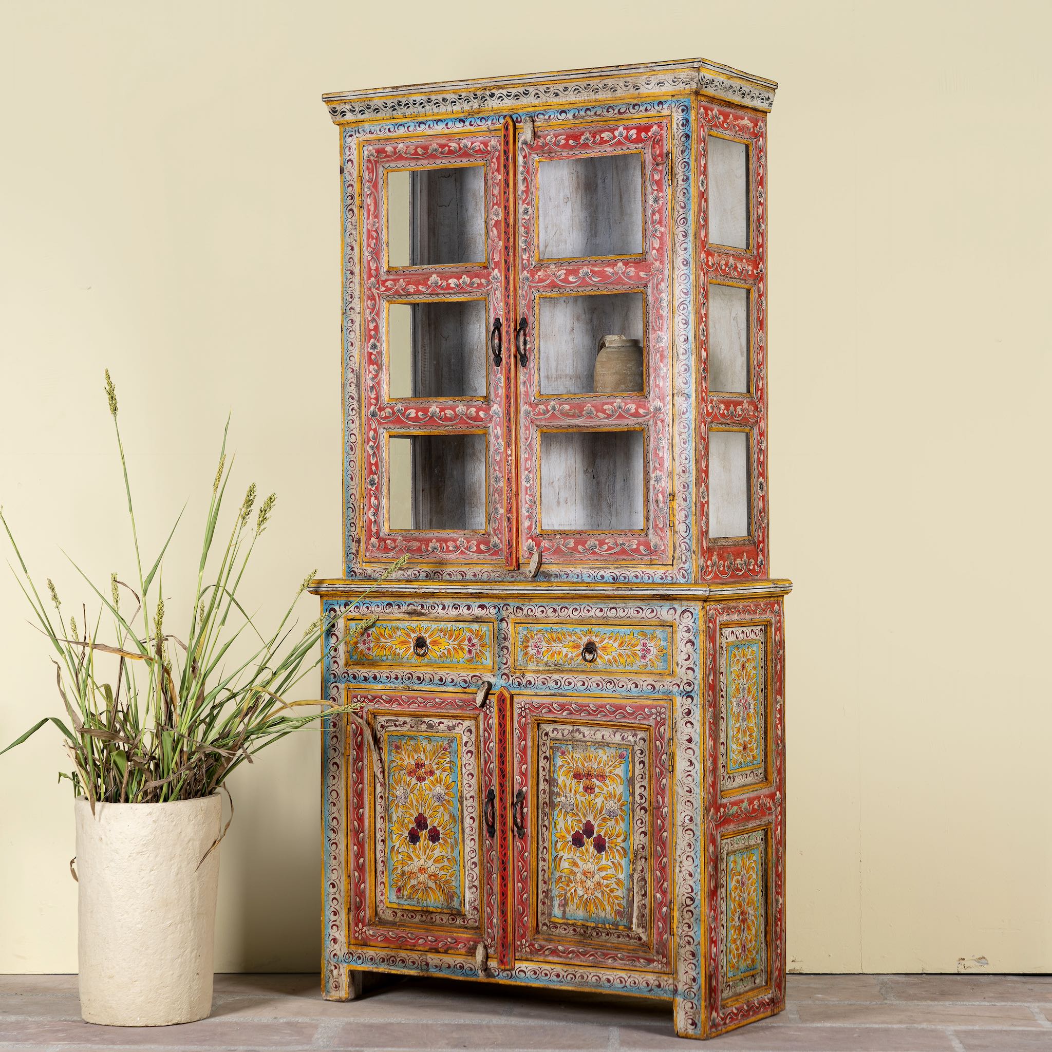 Side angle image of a hand-painted two-part showcase made of reclaimed wood with floral motifs; unique furniture for a boho chic living room, 94 × 48 × 203 cm.