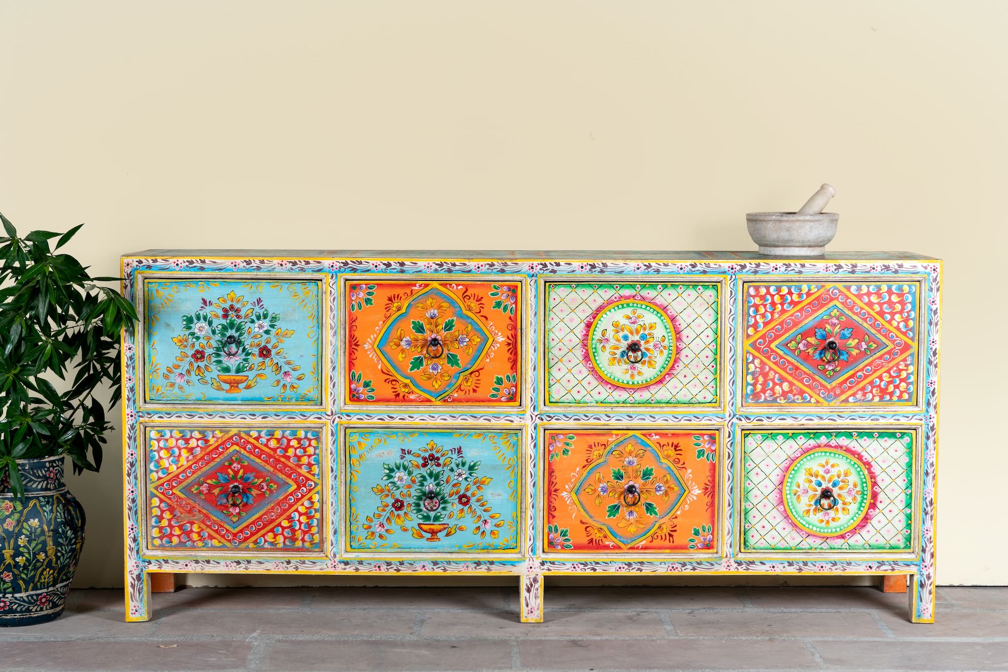 Image of a hand painted sideboard with 8 drawers made of natural mango wood; artisanal chest for bohemian interior, 200 × 40 × 90 cm.