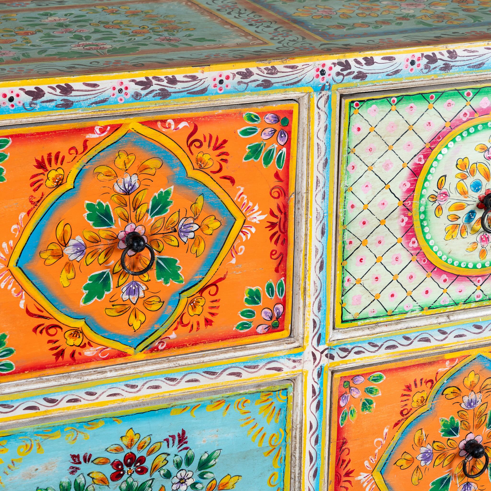 Close up image of a hand painted sideboard with 8 drawers made of natural mango wood; artisanal chest for bohemian interior, 200 × 40 × 90 cm.