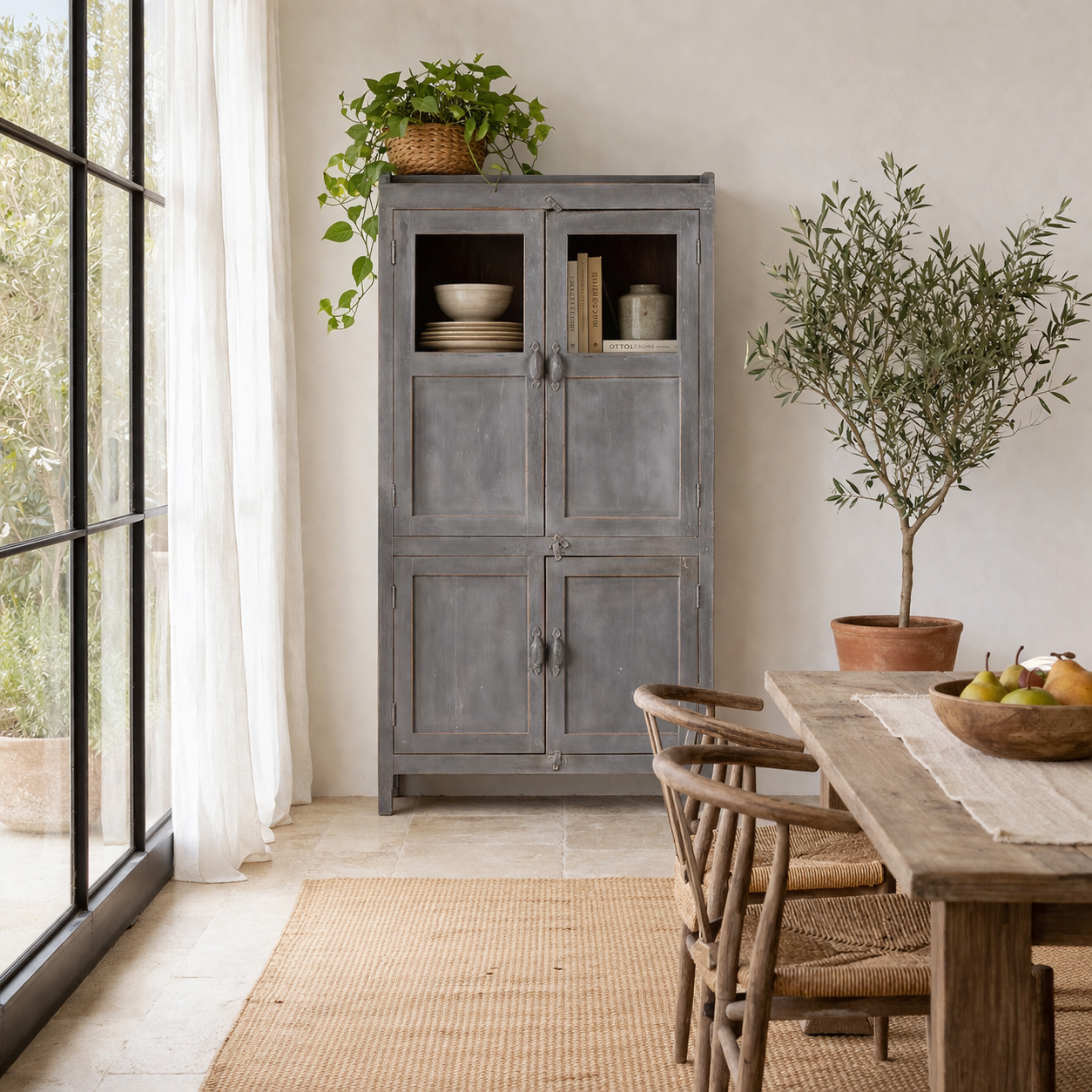 Lifestyle image of a shabby chic teak wood cabinet with glass doors and natural reclaimed finish – sustainable furniture ideal for vintage-style dining and living spaces.