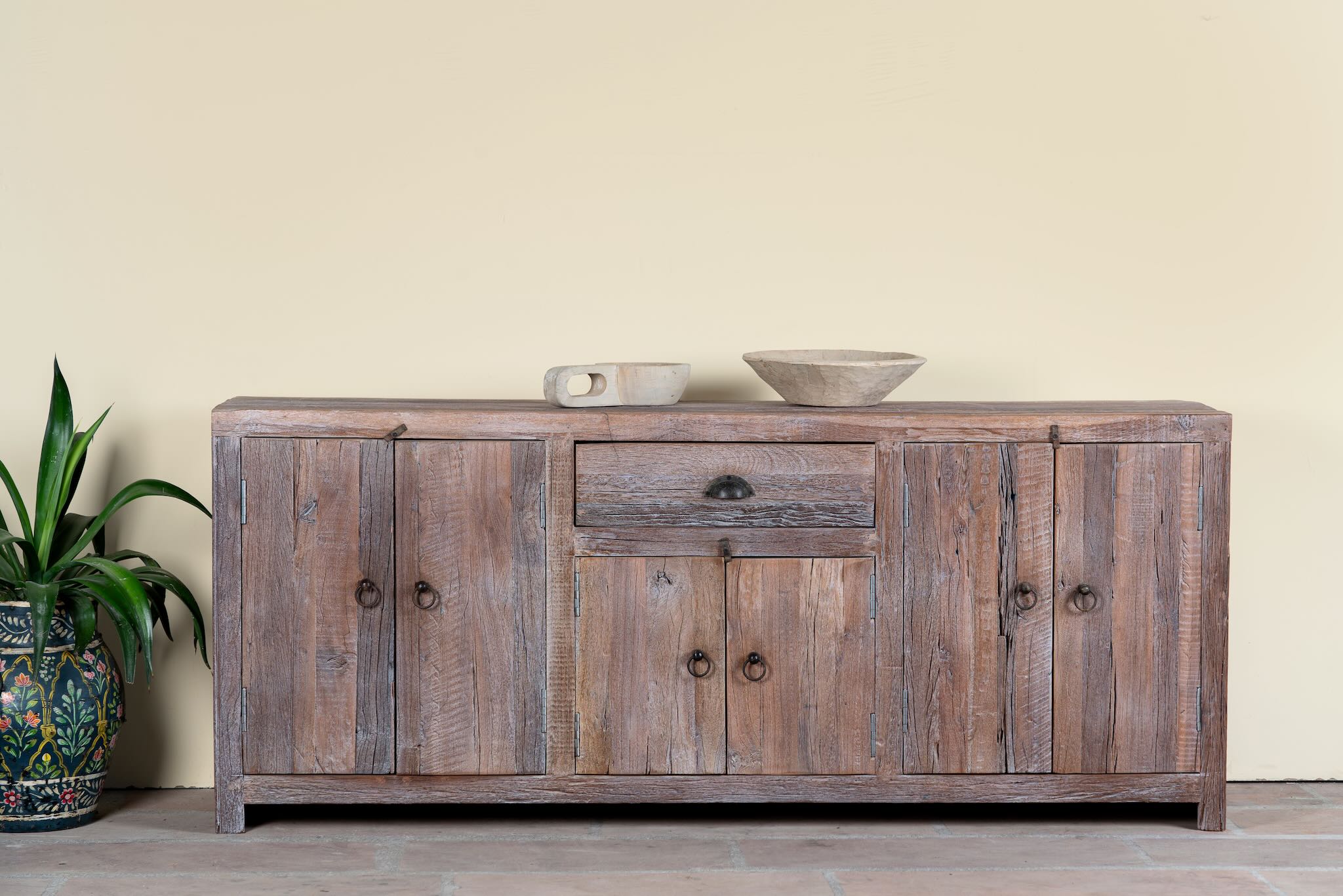 Reclaimed wood sideboard Devina in rustic minimalistic style with cabinet doors and central drawer. A sustainable furniture piece showcasing natural wood grain and timeless simplicity.