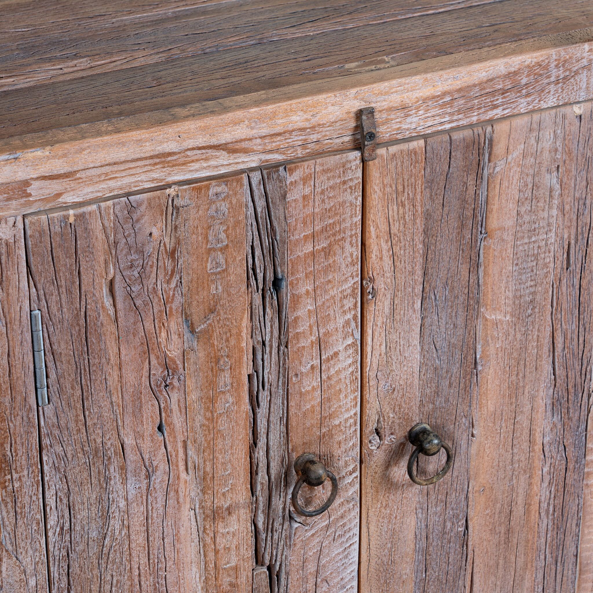 Close up image of a reclaimed wood sideboard Devina in rustic minimalistic style with cabinet doors and central drawer. A sustainable furniture piece showcasing natural wood grain and timeless simplicity.