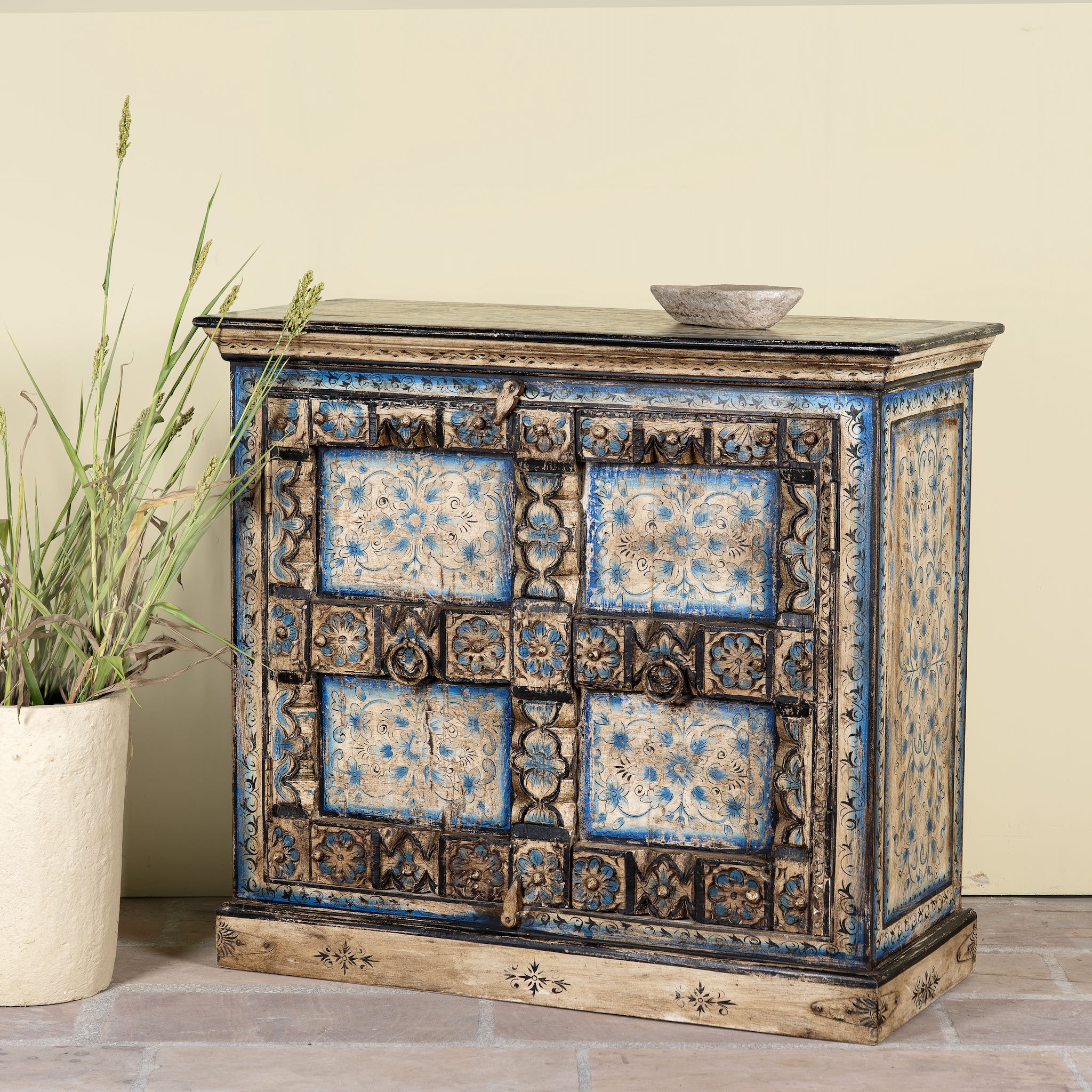 Side angle image of a cupboard made from an antique Indian old door, hand painted cabinet with blue floral details; boho style teak wood furniture, 115 × 50 × 104 cm.