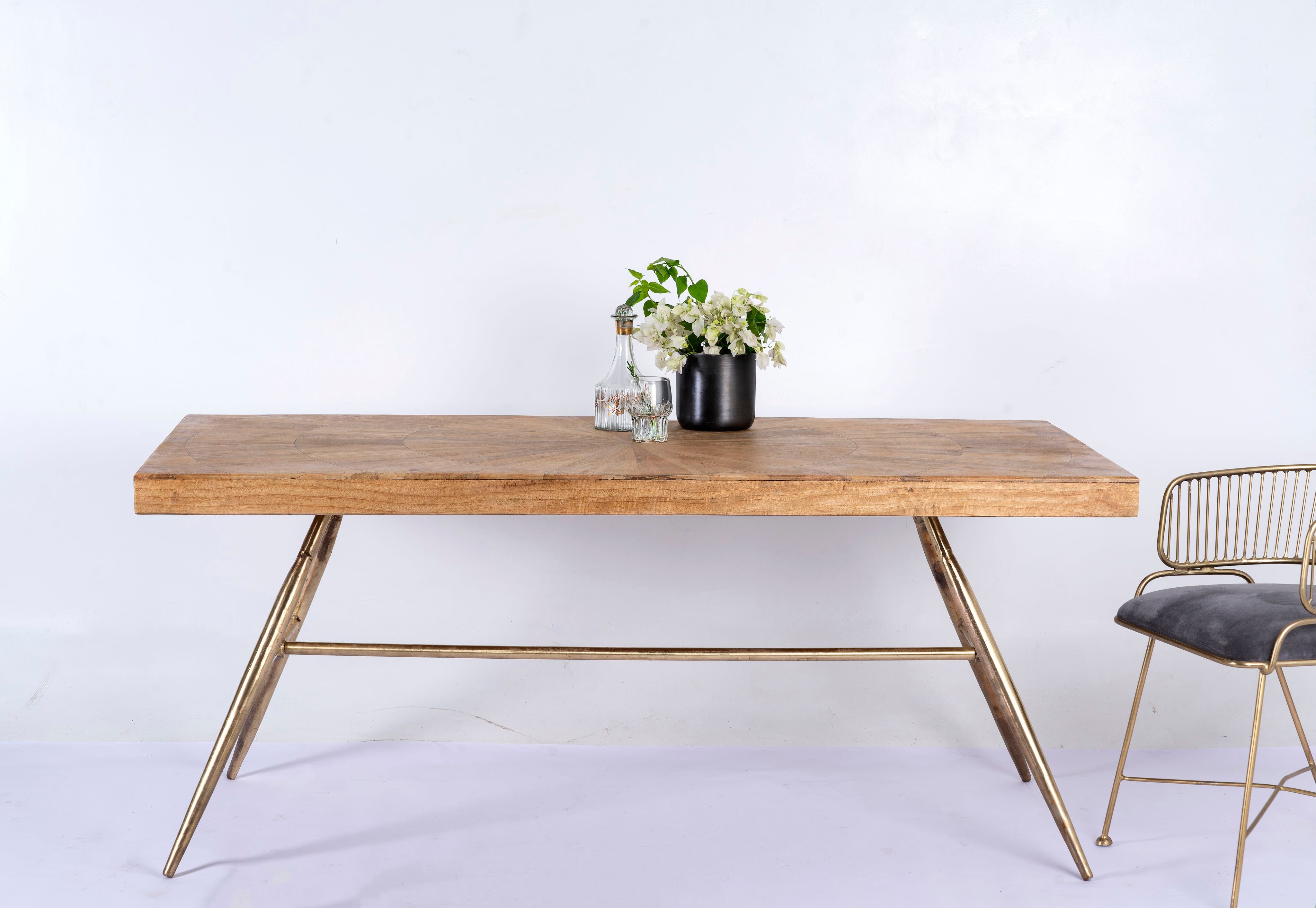 Shankhin mango wood dining table featuring an intricately patterned natural wood tabletop with a brass-plated iron base and contemporary industrial design, 180cm.