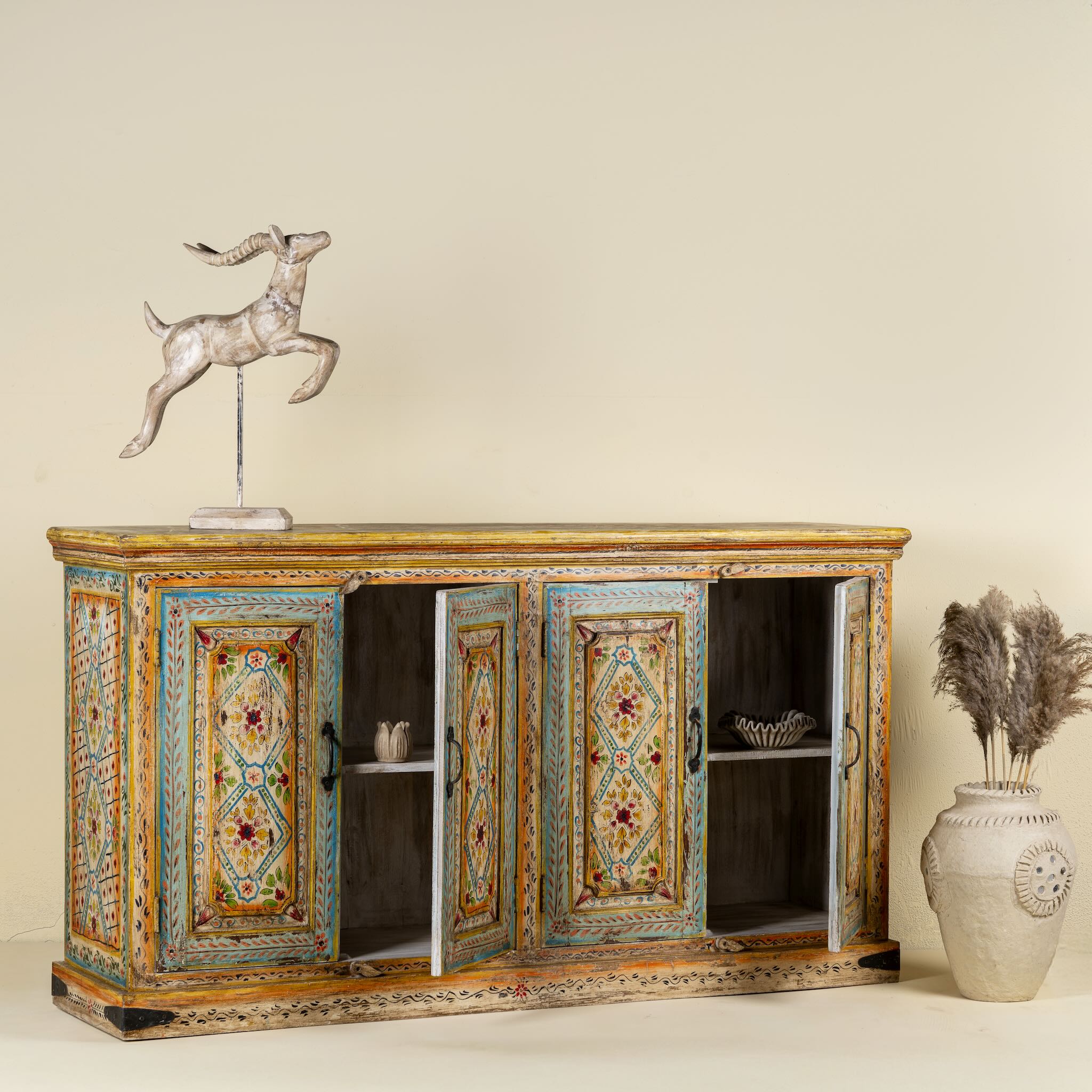 Side angle image with open doors of a hand painted wooden dresser with floral and geometric motifs, reclaimed wood living room furniture in vintage boho style, 170 × 45 × 95 cm.