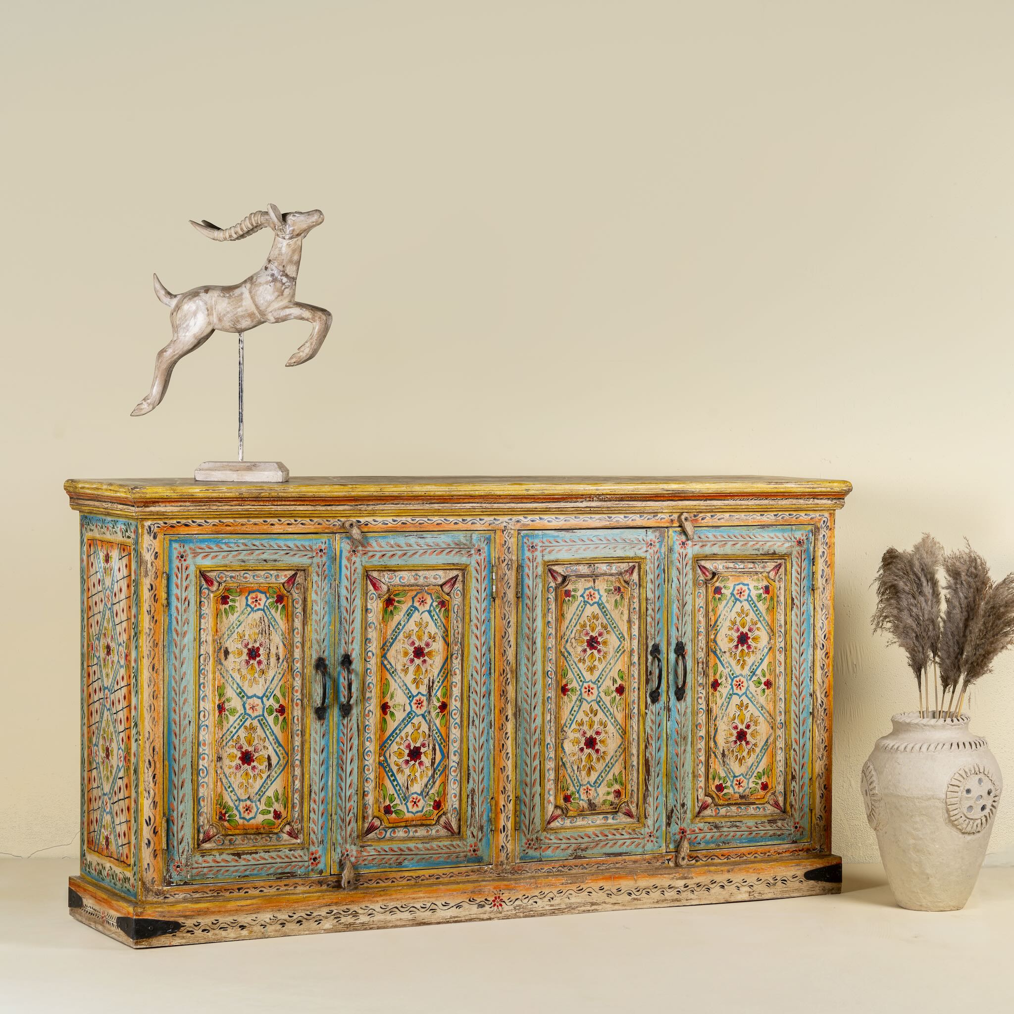 Side angle image of a hand painted wooden dresser with floral and geometric motifs, reclaimed wood living room furniture in vintage boho style, 170 × 45 × 95 cm.