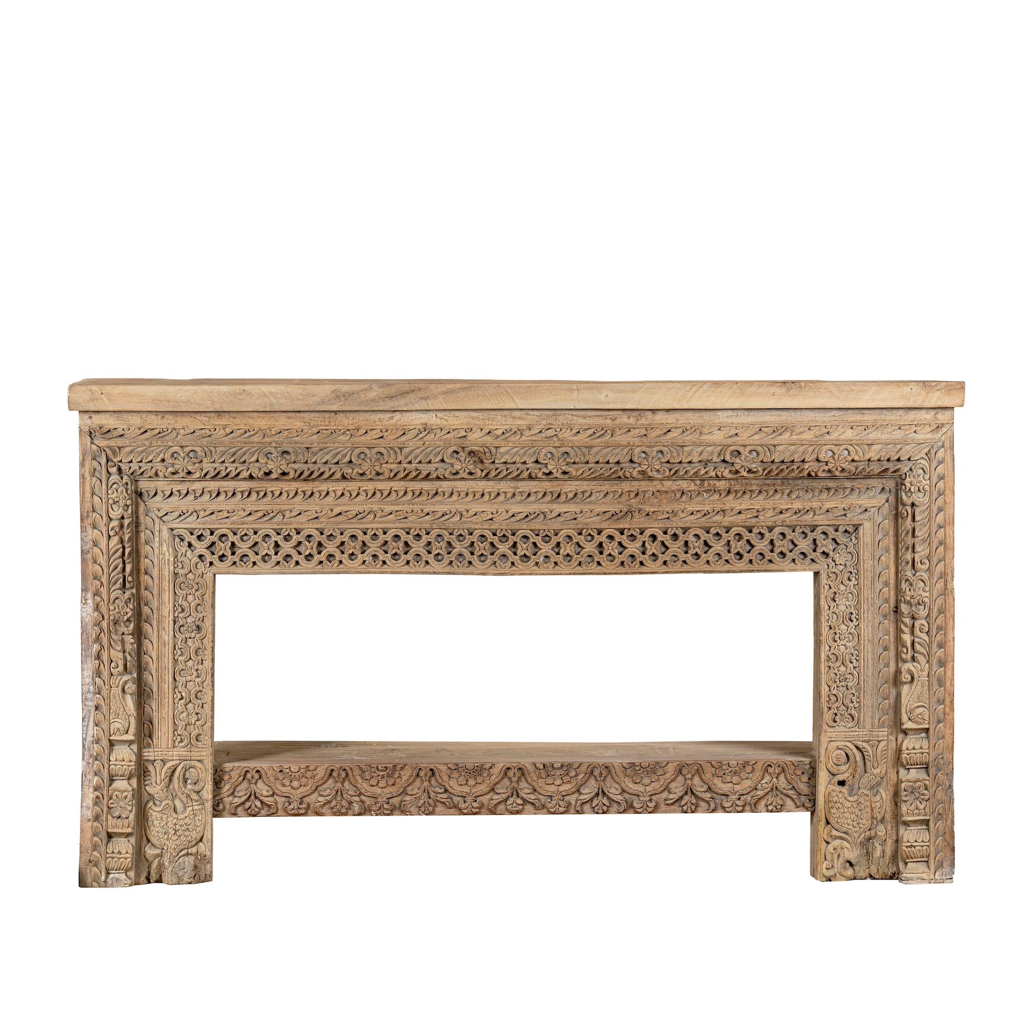 White background image of a ornate console table crafted from reclaimed teak wood and refurbished architectural elements, featuring intricate hand-carved detailing with floral and geometric motifs, showcasing a vintage artisanal aesthetic.