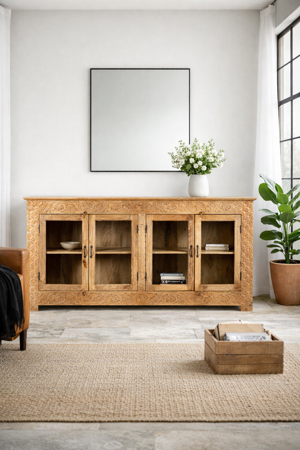 Lifestyle imagination of a hand-carved wooden showcase Barot made from natural mango wood, featuring detailed floral carvings across its front. A sustainable piece of Indian furniture online ideal for living room furniture with a Mediterranean and boho-style design.