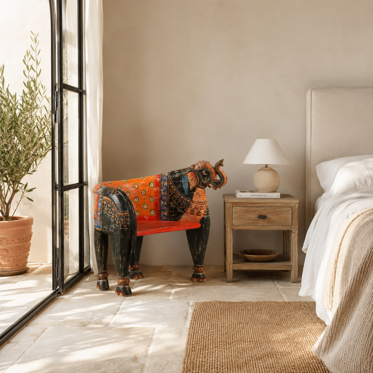 Lifestyle image of a elephant-shaped armchair crafted from reclaimed wood, featuring intricate hand-painted details in vibrant red, orange, green, and multi coloured floral patterns, with sculpted elephant head and legs for a whimsical, artistic touch.