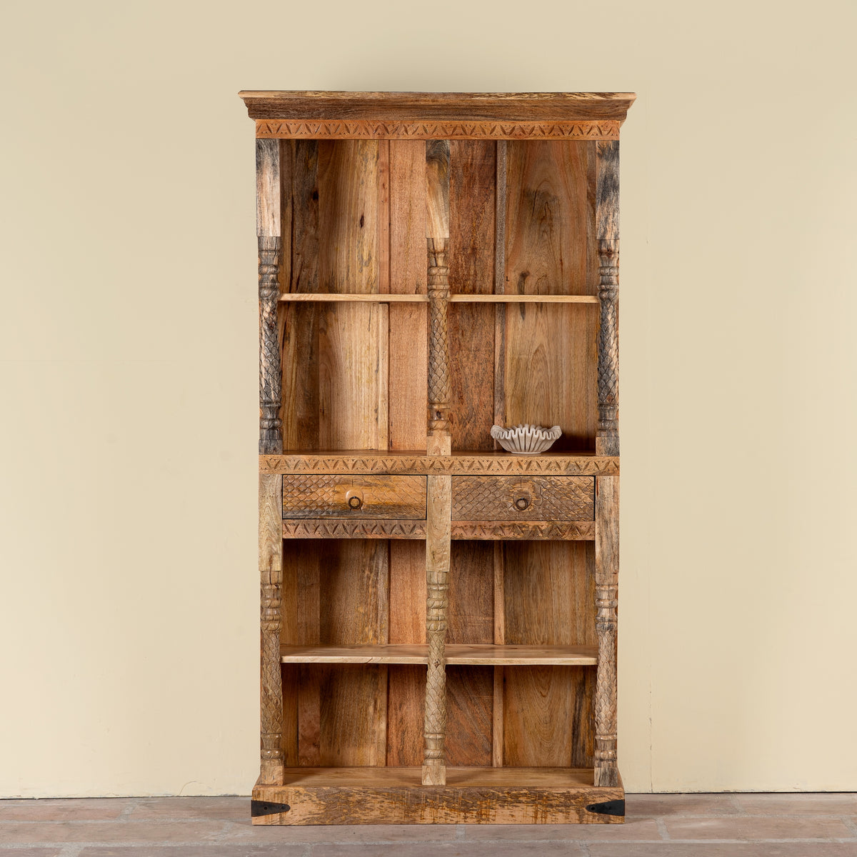 Image of a handcrafted mango wood bookshelf with carved detailing – mango wood shelving and carved wooden furniture in a warm brown finish for timeless interiors.