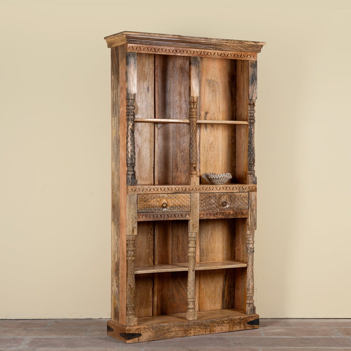 Side angle image of a handcrafted mango wood bookshelf with carved detailing – mango wood shelving and carved wooden furniture in a warm brown finish for timeless interiors.