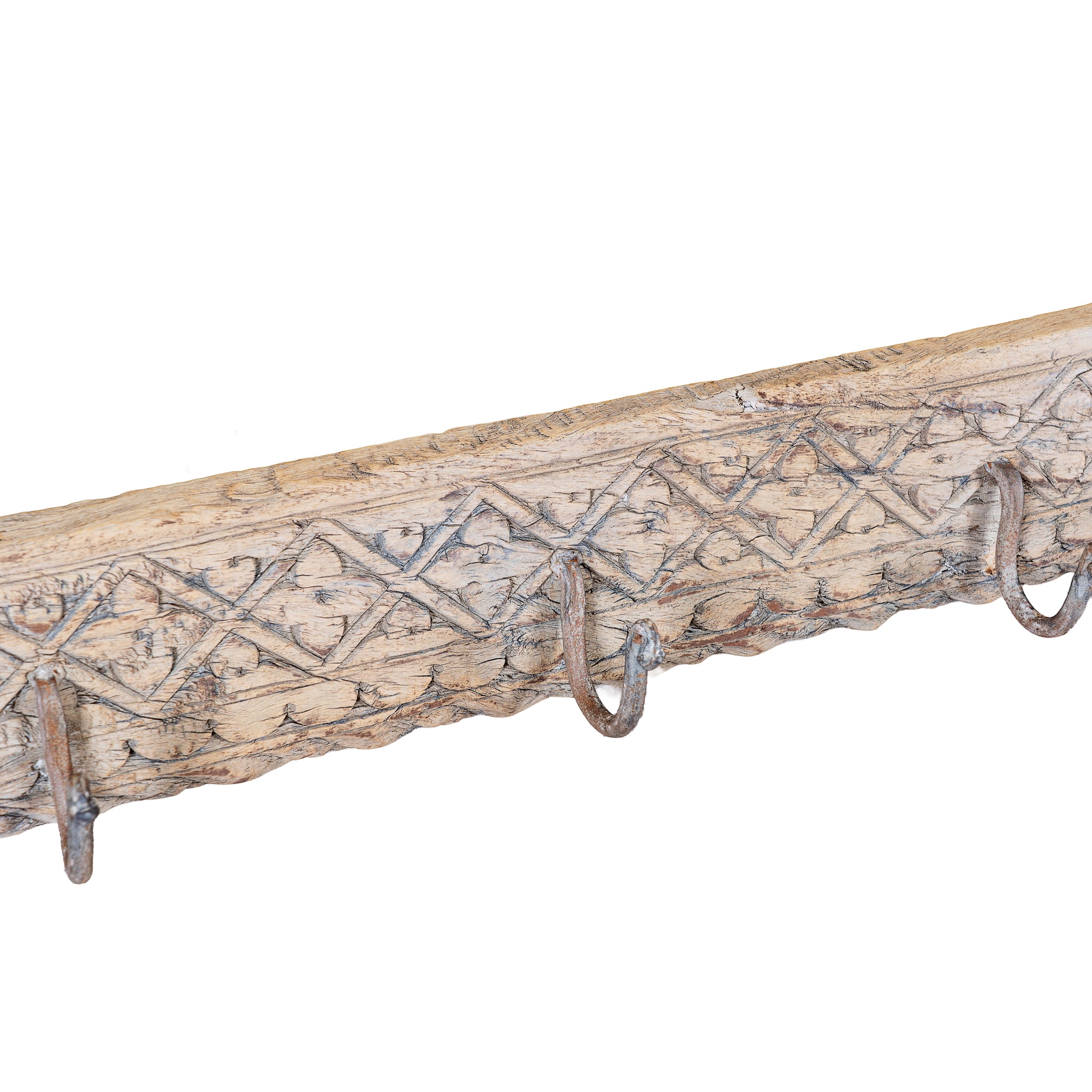 Close up image of a Temple Carved Hook Board handcrafted from an antique Indian reclaimed wood architectural element with hand-carved floral details, bleached finish and eight iron hooks, 150x7x5cm.