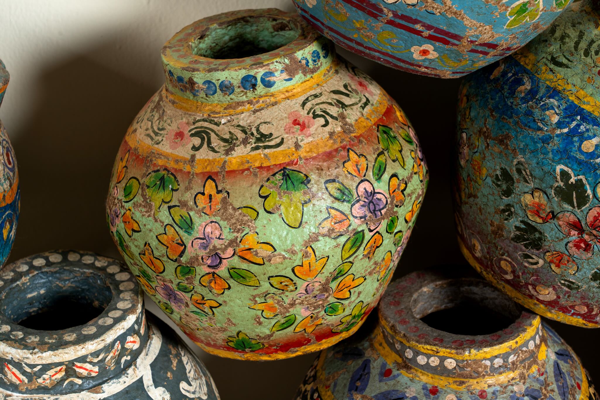 Close up image of hand-painted papier-mâché vases from India with floral folk-art designs in vibrant mixed colors. Unique Indian decor and decorative art objects handcrafted using traditional methods.