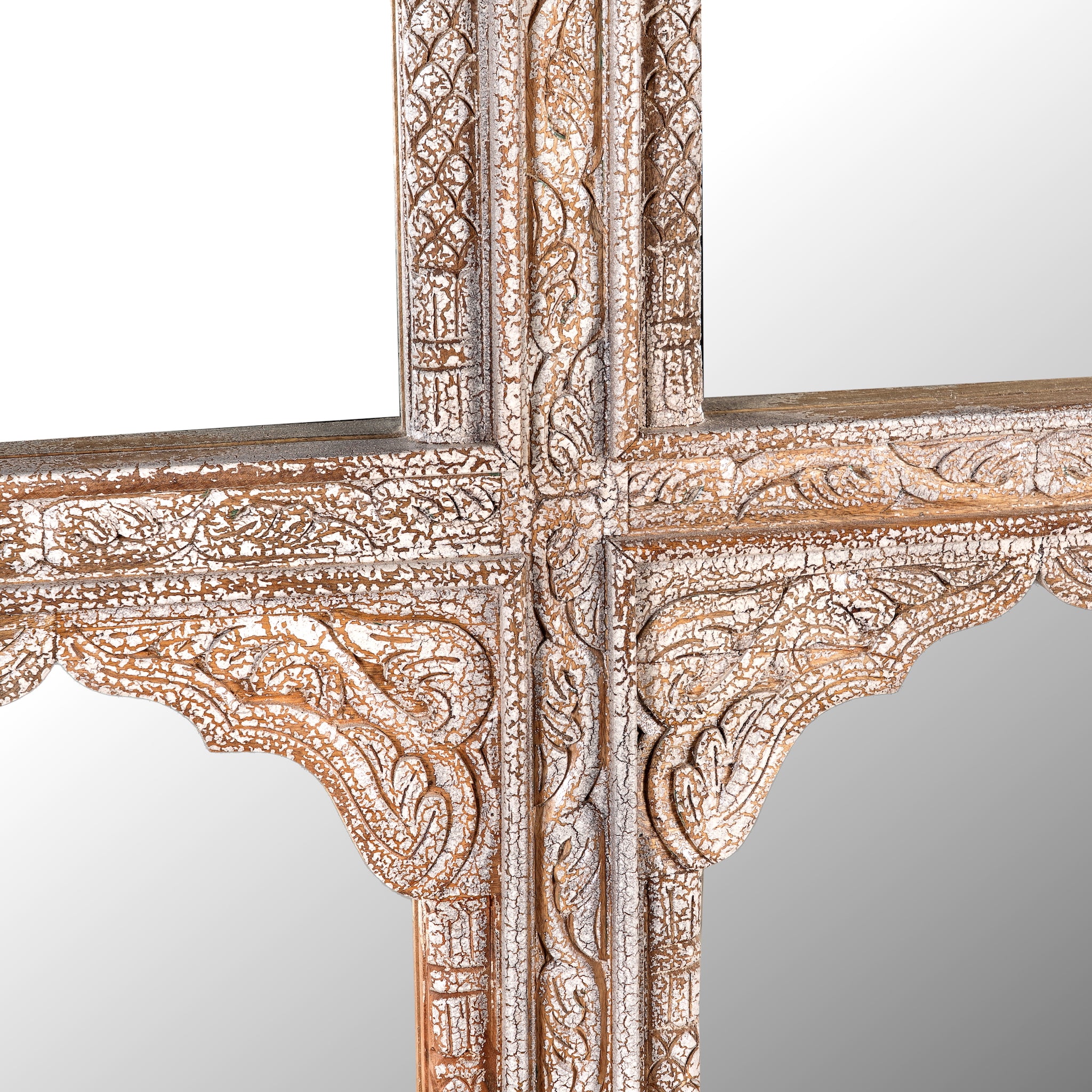 Close up image of a hand-carved wall mirror Jamnagar made from solid mango wood with floral design. A bold piece of Indian furniture online blending craftsmanship and natural beauty.
