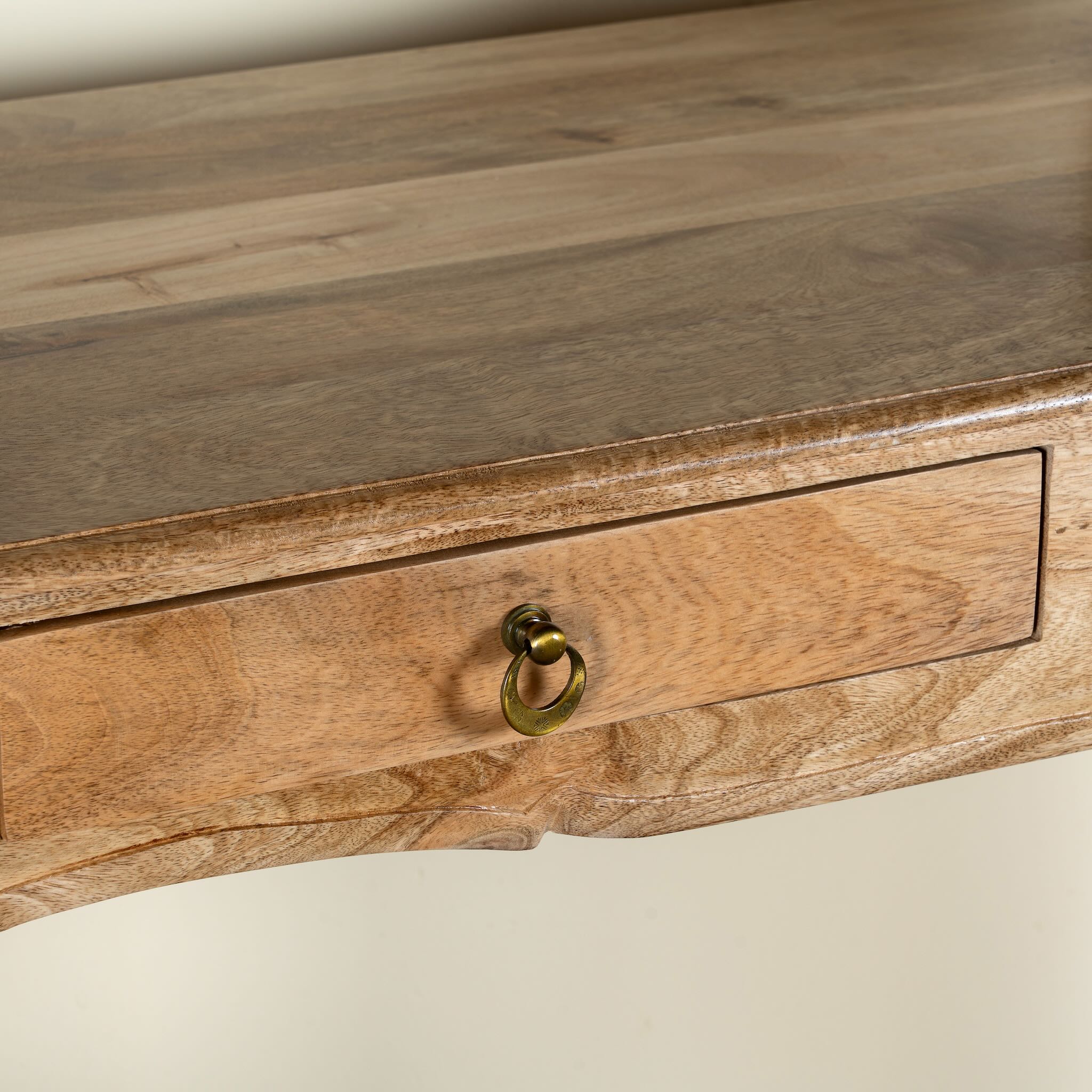 Close up image of a desk made of natural mango wood with 2 drawers and carved legs.